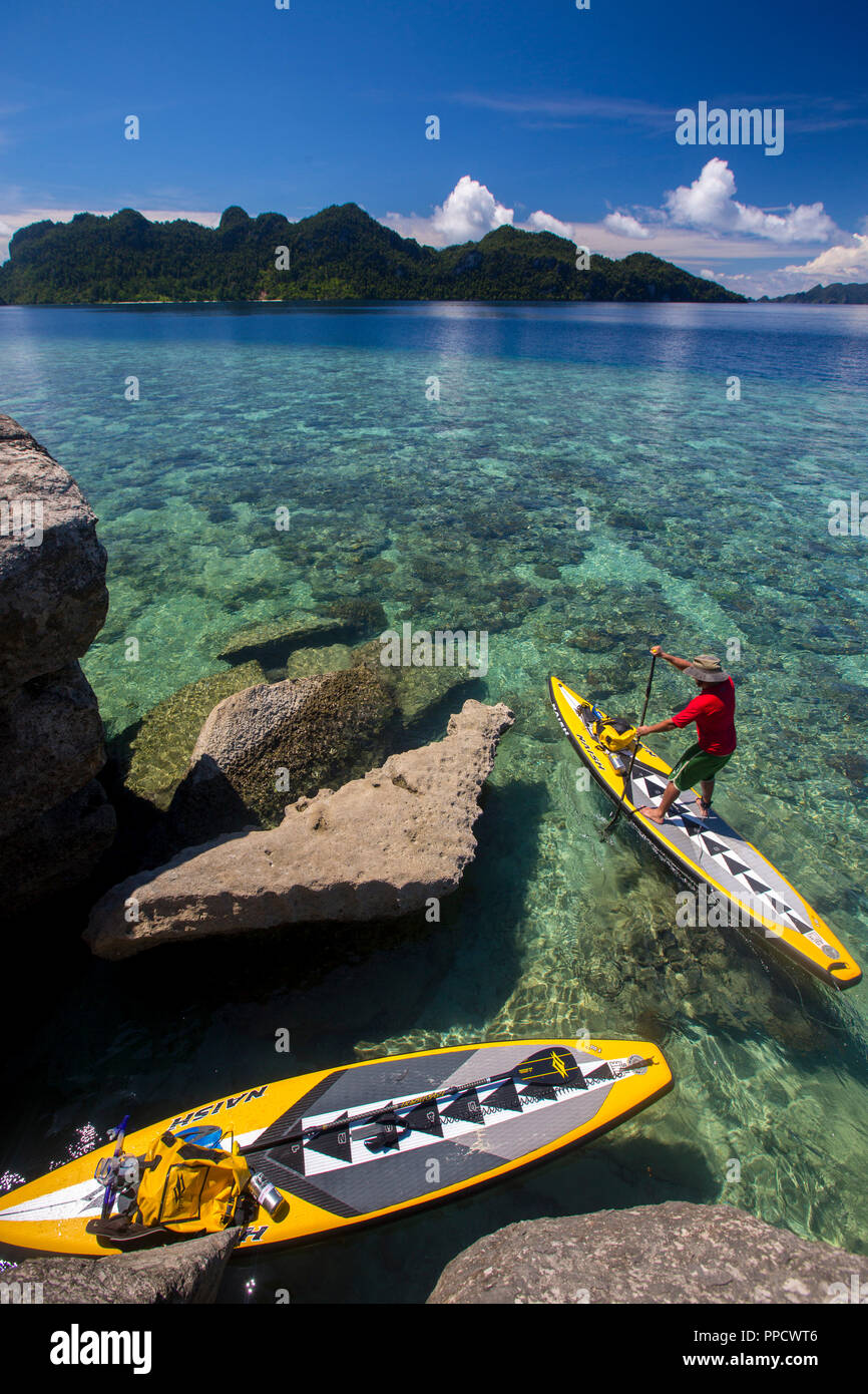 Paddleboard und Mann paddleboarding im Meer, Misool, Raja Ampat, Indonesien Stockfoto