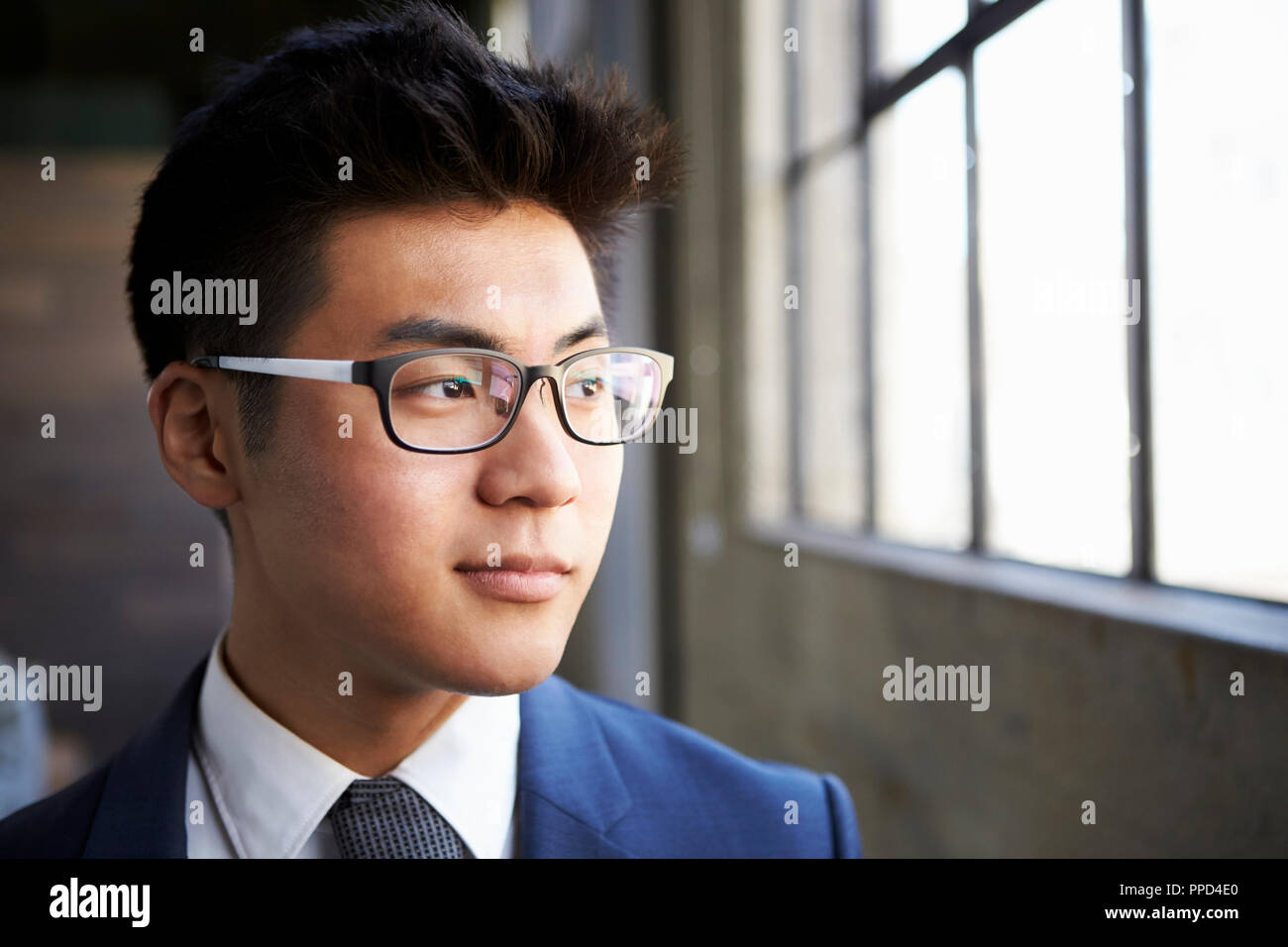 Junge asiatische Geschäftsmann Blick aus Fenster schließen Stockfoto
