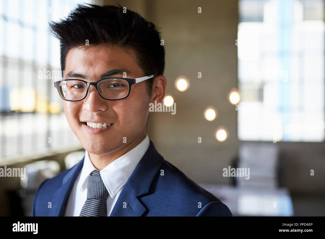 Junge asiatische Geschäftsmann lächelnd in die Kamera, Kopf und Schultern Stockfoto