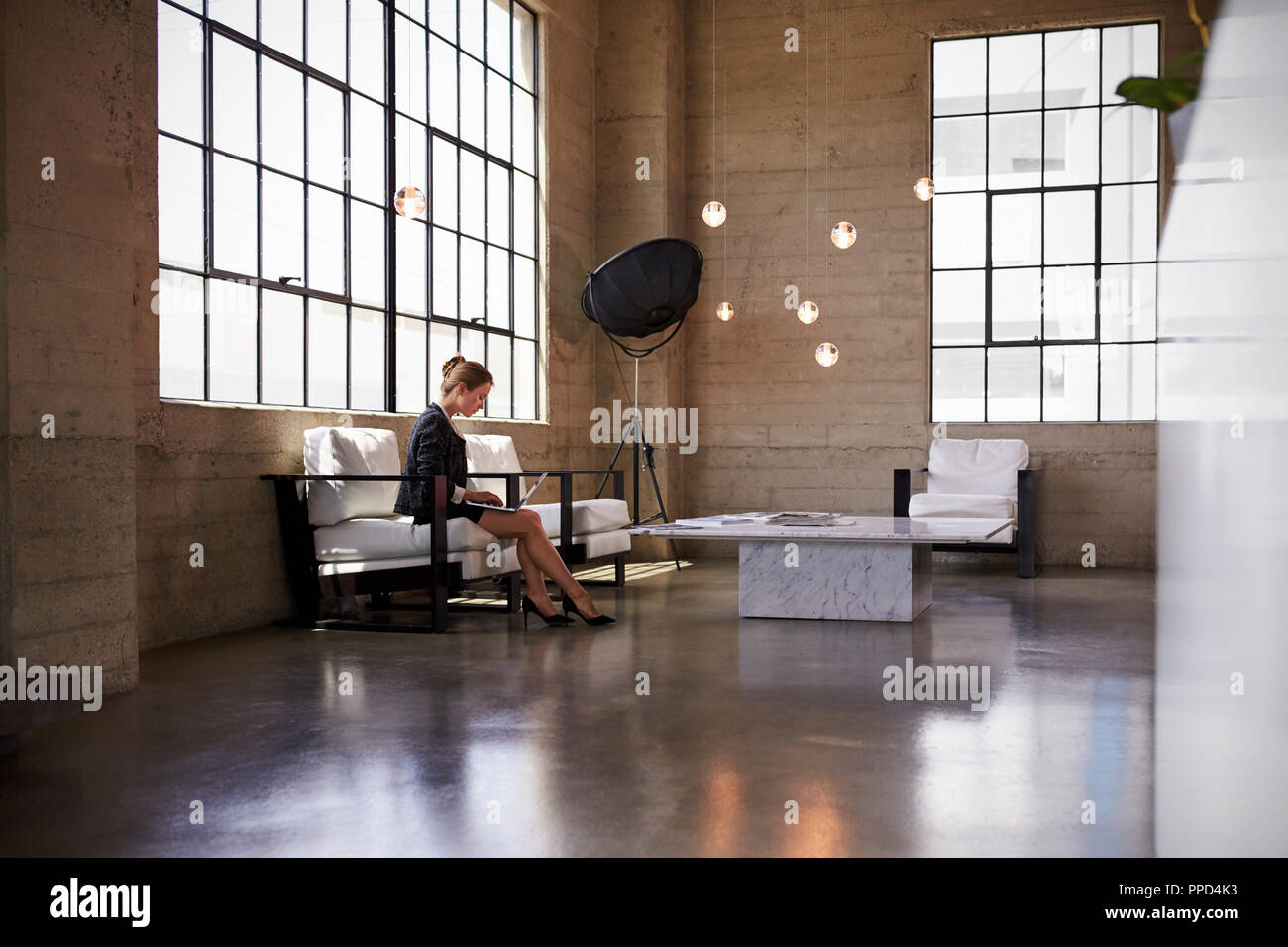 Junge Geschäftsfrau mit Laptop in der Empfangshalle Stockfoto
