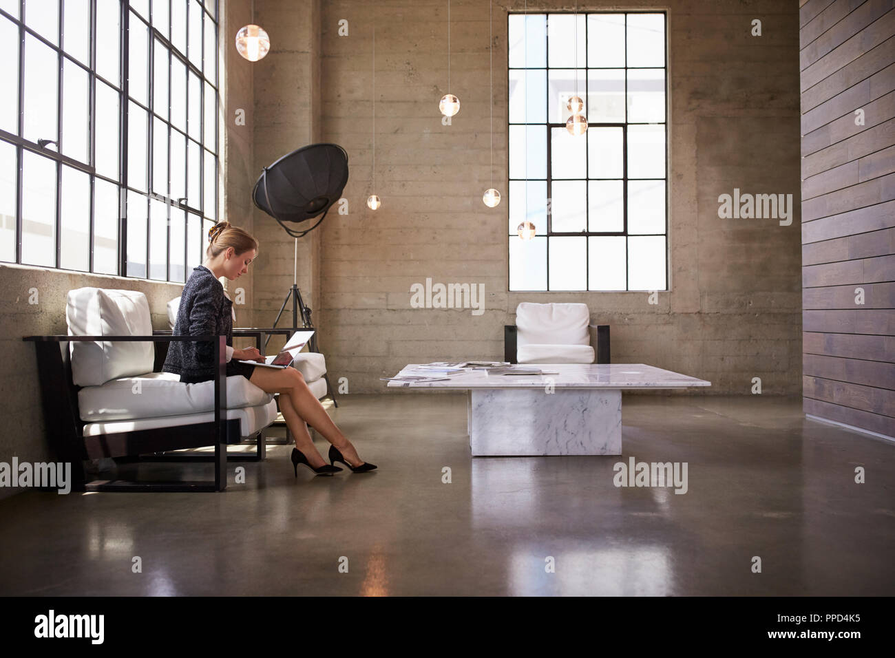 Junge Geschäftsfrau mit Laptop in der Empfangshalle, in der Nähe Stockfoto