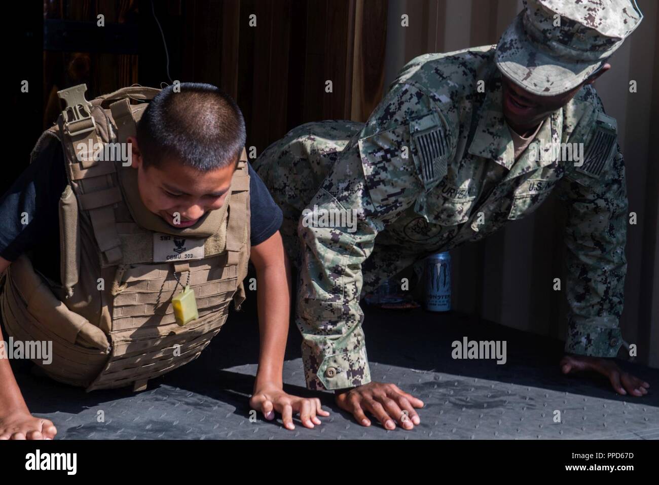 ANGELES (Sept. 2, 2018) Ausrüstung Fahrer Constructionman Tyrell Puryear, Bau Bataillon Wartungseinheit 303 angeschlossen ist, hat eine Push-up-Wettbewerb mit einem Kind trägt eine Kevlar Weste bei einer militärischen Display und Demo auf dem Schlachtschiff Iowa Museum während Los Angeles Flotte Woche (LAFW). LAFW ist eine Gelegenheit für die amerikanische Öffentlichkeit die Navy, Marine Corps und Küstenwache Teams zu treffen und America's Meer Dienstleistungen Erfahrung. Während der Fleet Week, service Mitglieder beteiligen sich an verschiedenen gemeinschaftlichen Service Veranstaltungen, Showcase Funktionen und Geräten für die Gemeinschaft, und die Gastfreundschaft genießen Stockfoto