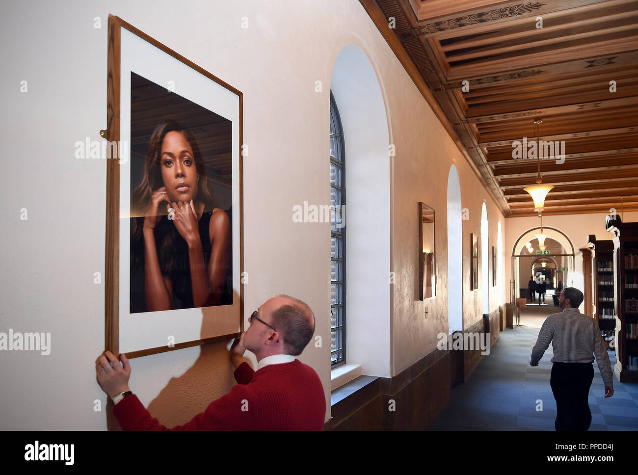 Leiter der Ausstellungen und öffentlichen Programmen Chris Burgess stellt ein Porträt der Schauspielerin Naomie Harris, die Teil der neuen Ausstellung "Schwarze Cantabs: Geschichte der Filmemacher, bestehend aus 14 Porträts von schwarz Cambridge Absolventen. Stockfoto
