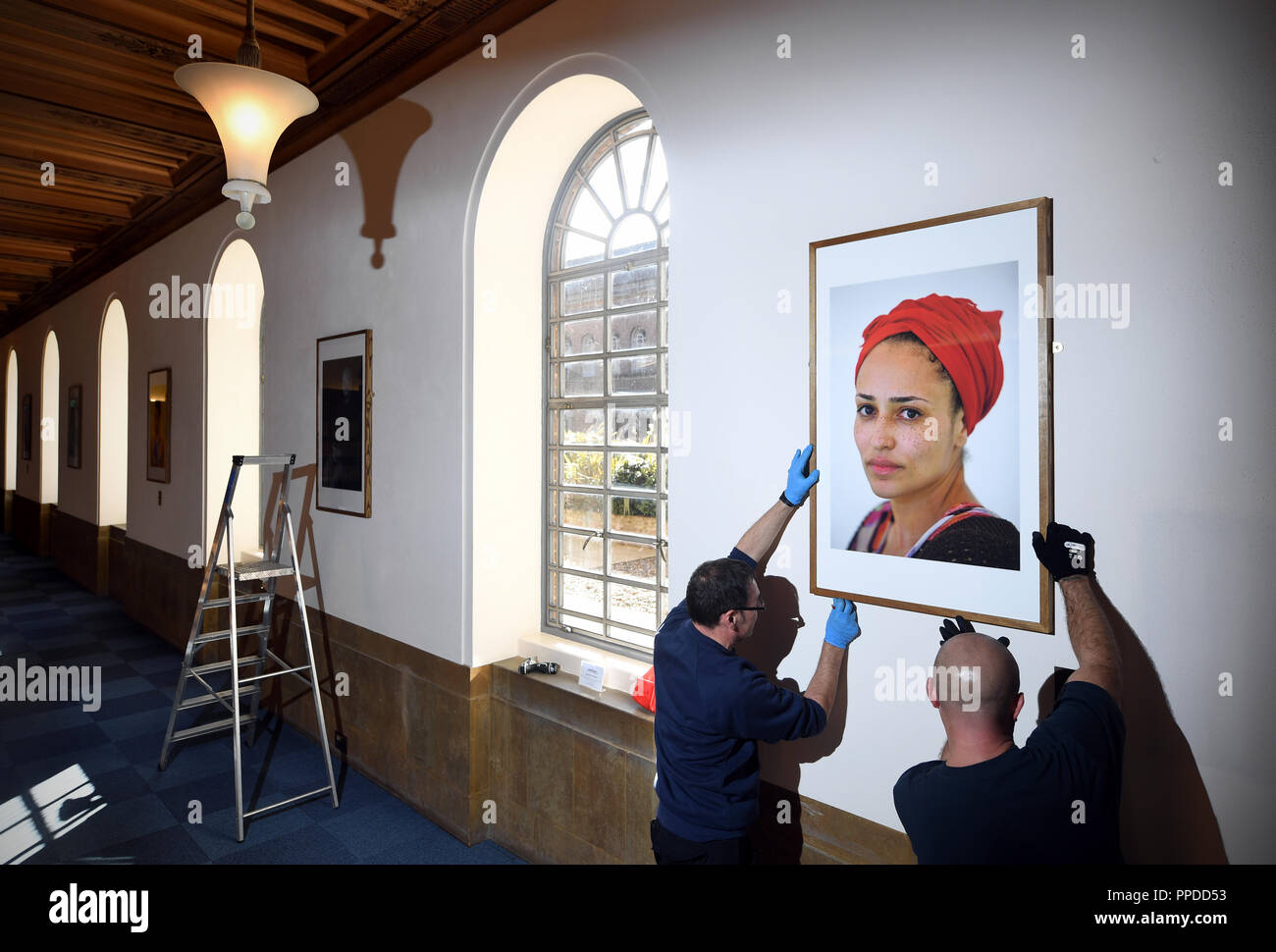 Der Cambridge University Library Zimmerleute hängen Sie ein Porträt der Schriftstellerin Zadie Smith, als Teil der neuen Ausstellung "Schwarze Cantabs: Geschichte der Filmemacher, der sich aus 14 Porträts von schwarz Cambridge Absolventen. Stockfoto