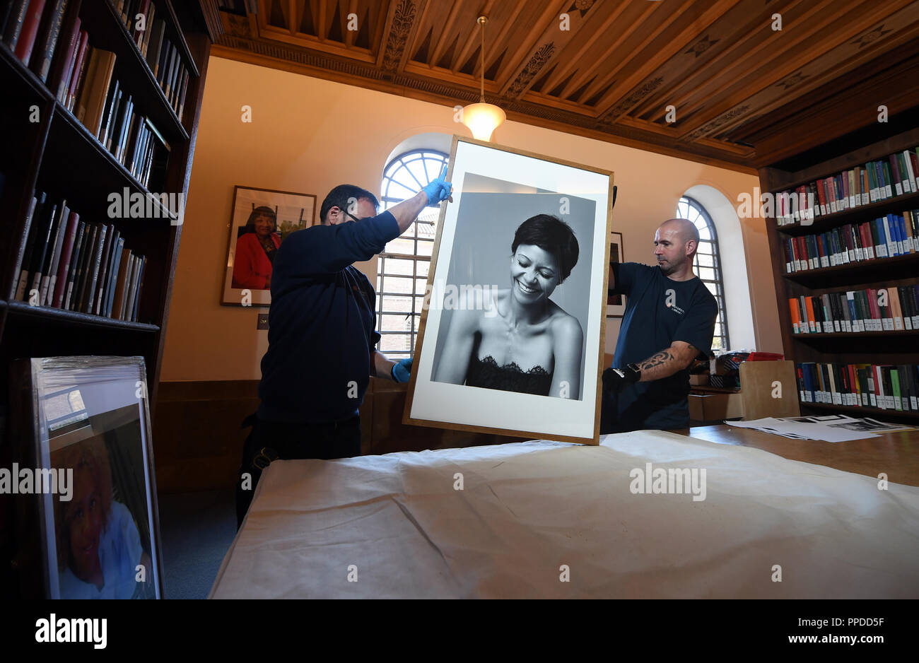 Der Cambridge University Library Schreiner bereiten Sie ein Porträt der Schauspielerin Thandie Newton zu hängen, als Teil der neuen Ausstellung "Schwarze Cantabs: Geschichte der Filmemacher, der sich aus 14 Porträts von schwarz Cambridge Absolventen. Stockfoto