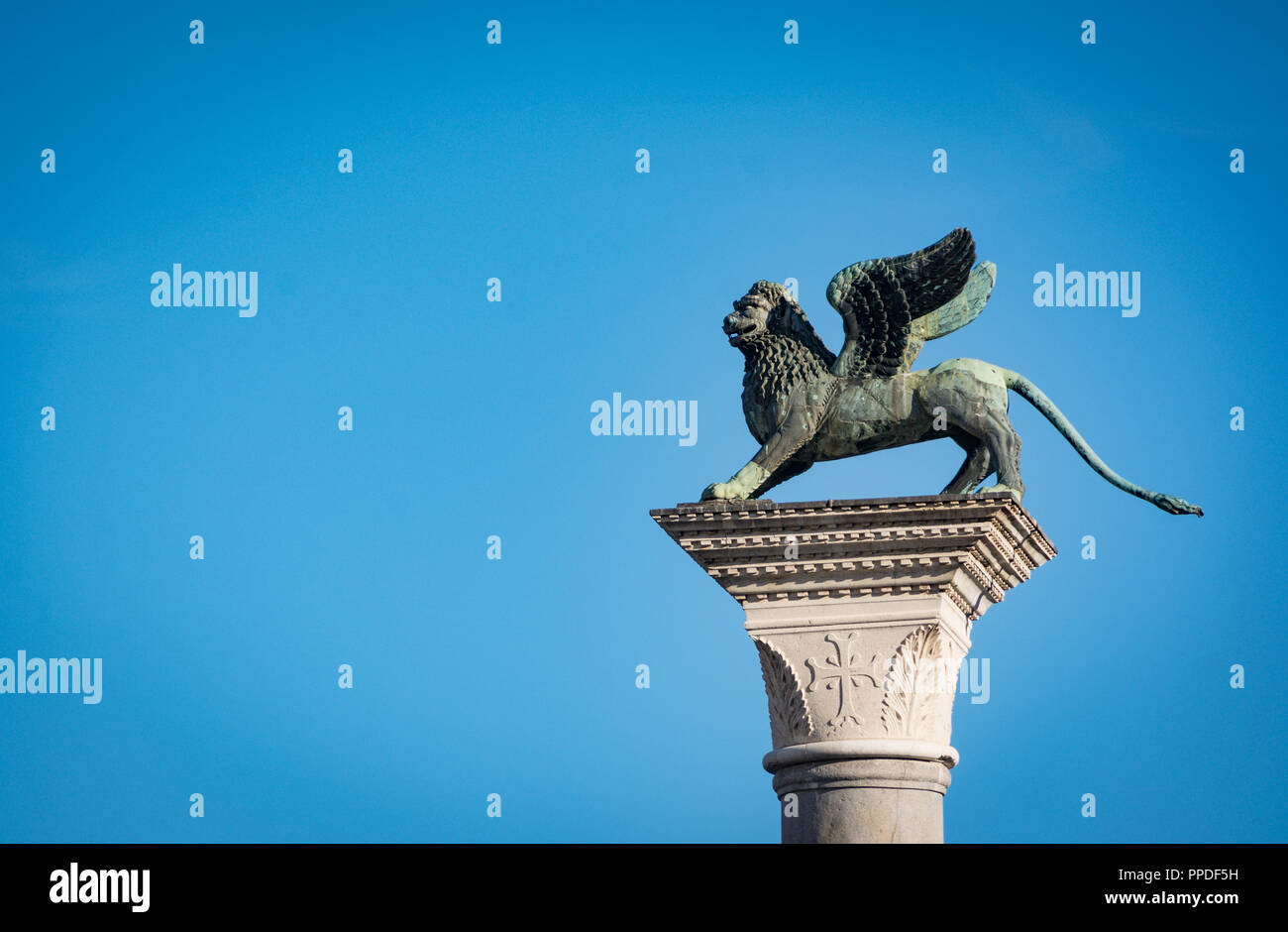 Der geflügelte Löwe von Venedig, das Symbol von San Marco, die steht auf einer hohen Säule auf der Piazza di San Marco. Am blauen Himmel isoliert. Die Stadt Venedig ein Stockfoto