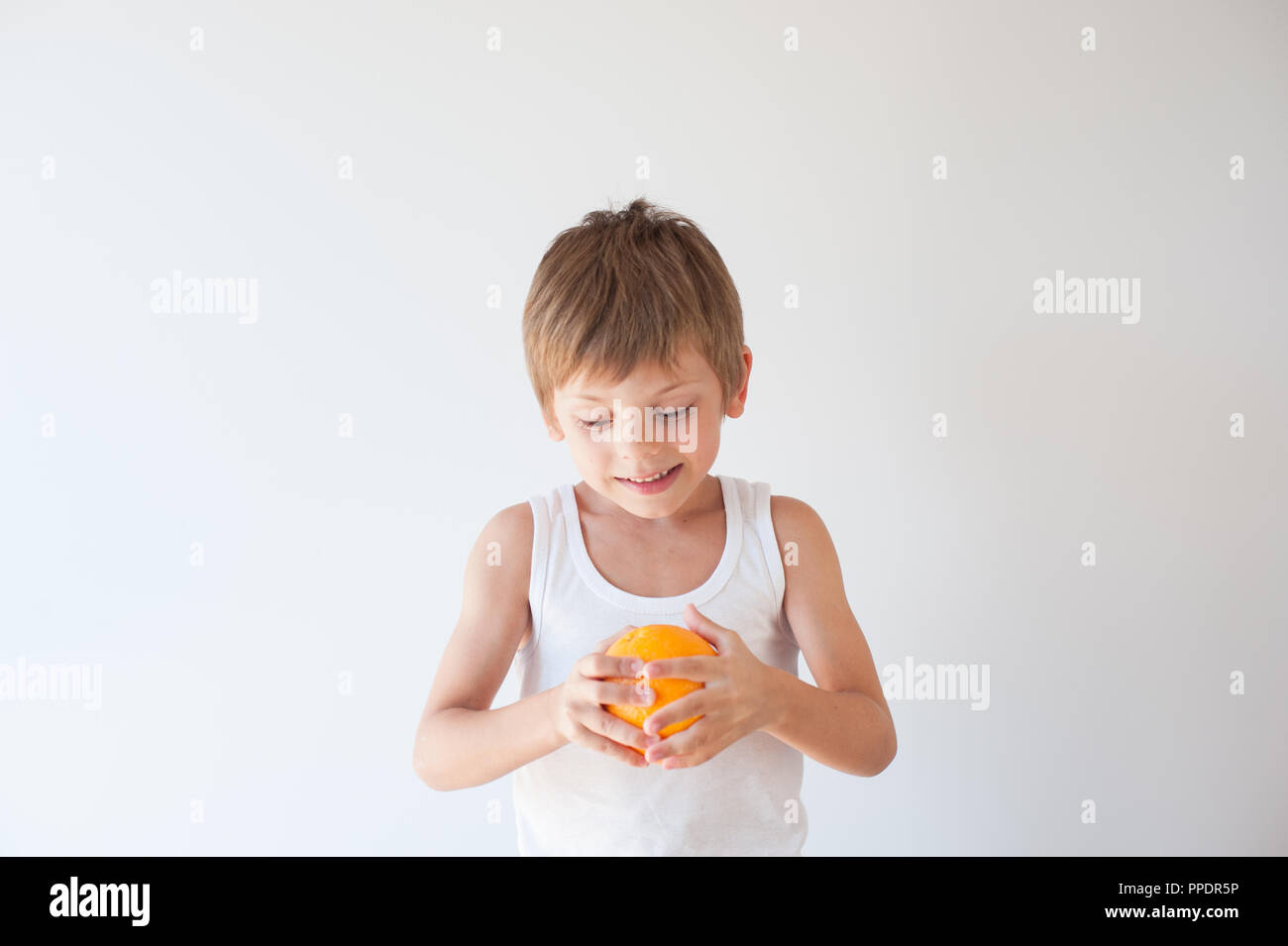 Gesunde kleine Kind in weißem T-Shirt, orange Frucht auf weißem Hintergrund Stockfoto