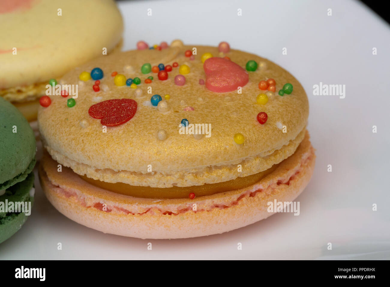 Hausgemachte sortierten Macarons schön mit bunten Herzen, grüner Tee und Gelb und Gold Farbe dekoriert Stockfoto