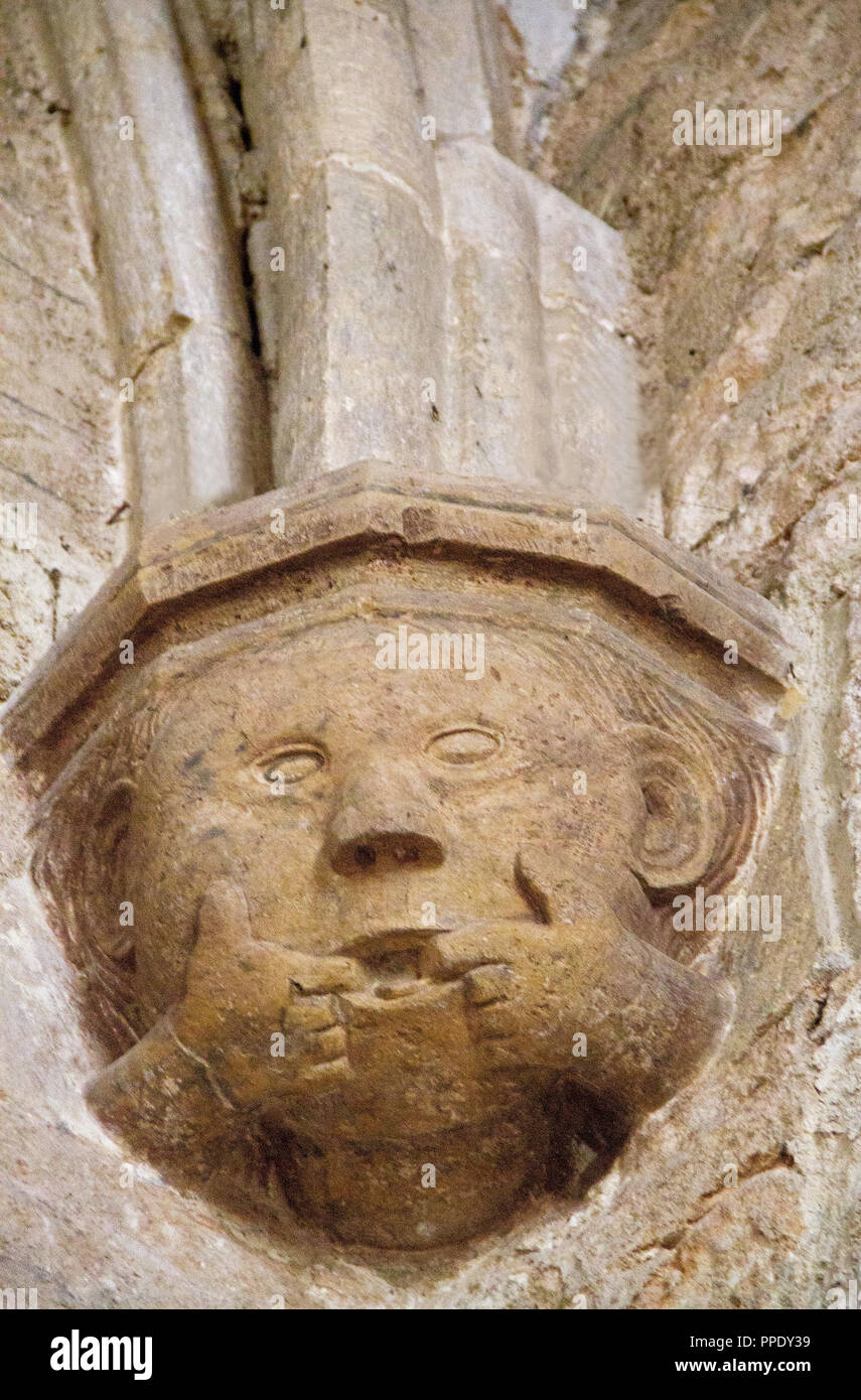 Lustige mittelalterliche Skulptur eines Kopf mit zwei Fingern im Mund, die Spalte in der Kathedrale von saint-fulcran in Lodeve, Frankreich Stockfoto