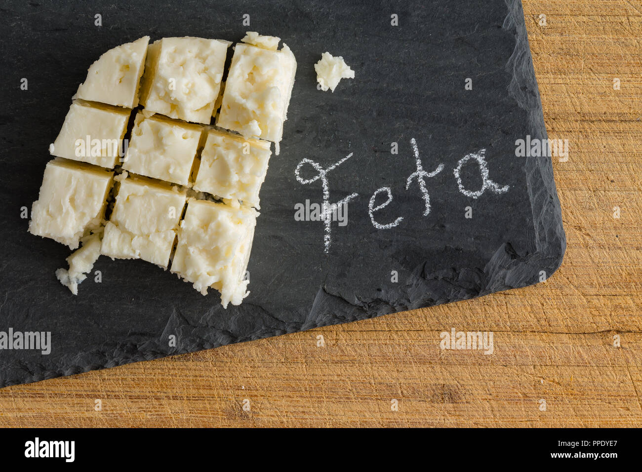 Gewürfelte Platte des traditionellen semi-soft krümelig griechischer Schafskäse auf einer Schiefertafel mit handschriftlichen Text - Feta - Neben der von oben gesehen Stockfoto