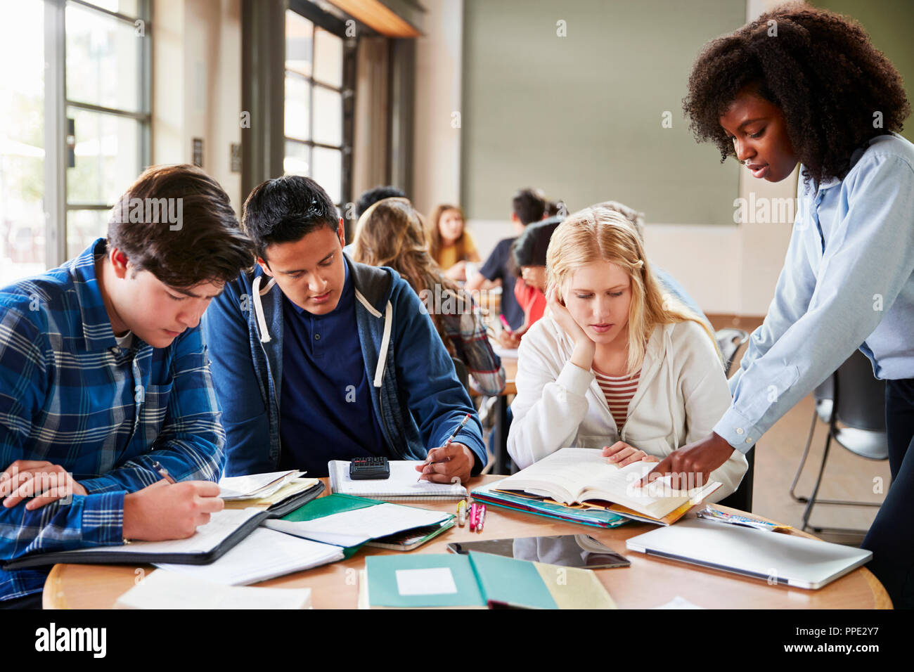 Gruppe von Schülerinnen, mit Lehrerin Arbeiten am Schreibtisch Stockfoto