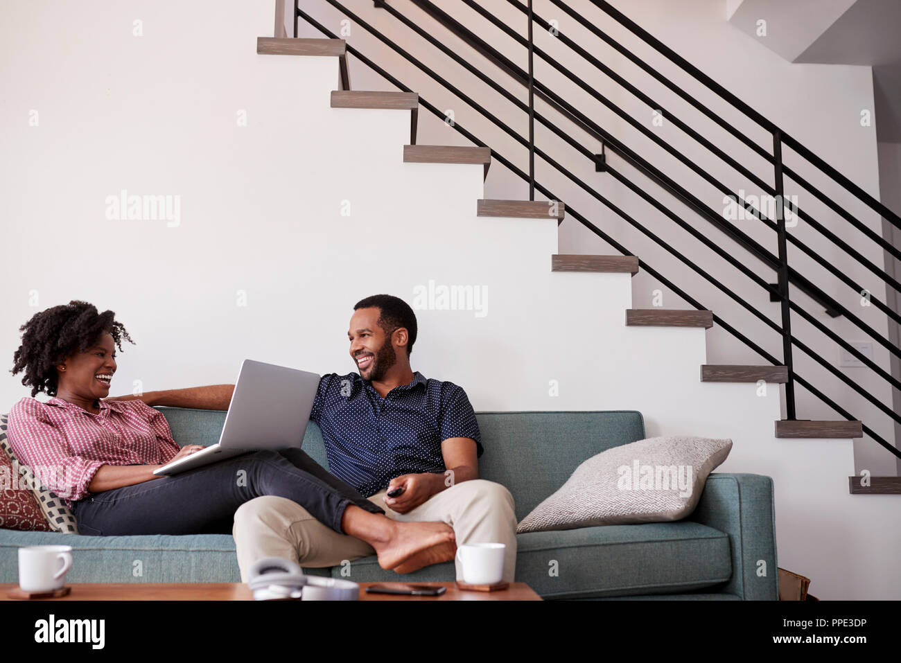 Paar sitzt auf einem Sofa zu Hause mit Frau mit Laptop Stockfoto