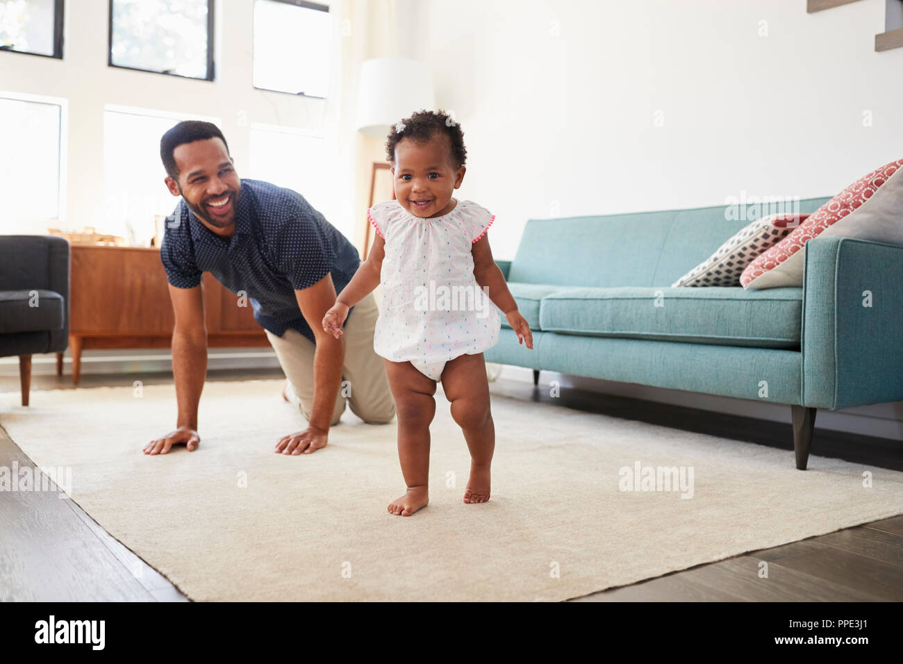 Vater Förderung Baby Tochter zu unternehmen erste Schritte zu Hause Stockfoto
