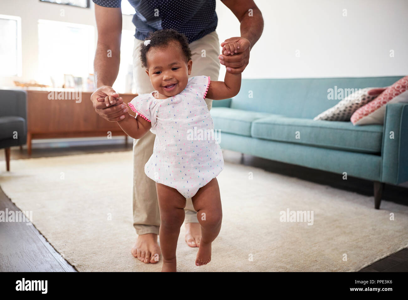 Vater Förderung Baby Tochter zu unternehmen erste Schritte zu Hause Stockfoto