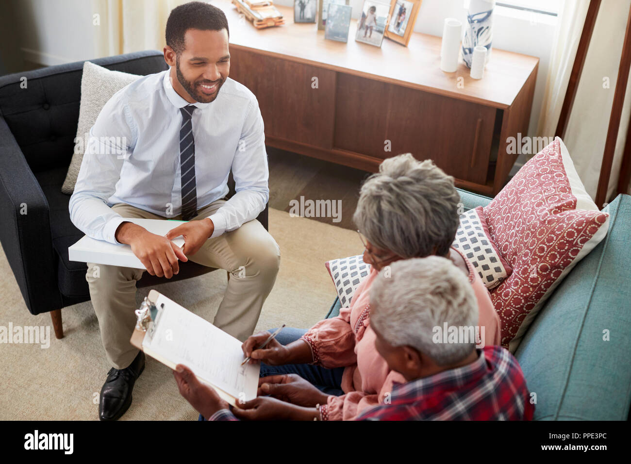 Senior Paar treffen mit männlichen Finanzberater zu Hause und Unterzeichnung des Dokuments Stockfoto