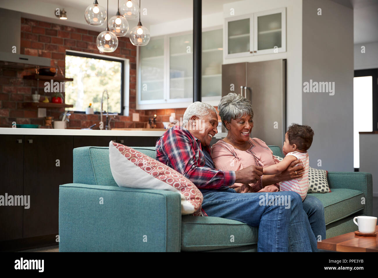 Großeltern auf dem Sofa mit Baby Enkelin zu Hause sitzen Stockfoto