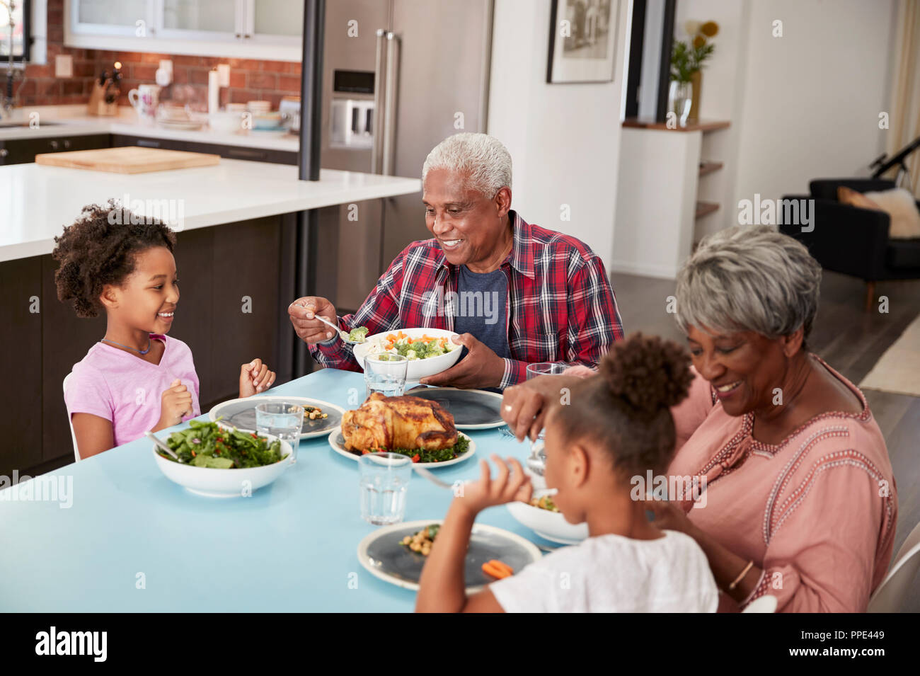 Großeltern genießen Mahlzeit zu Hause mit Enkelinnen Stockfoto
