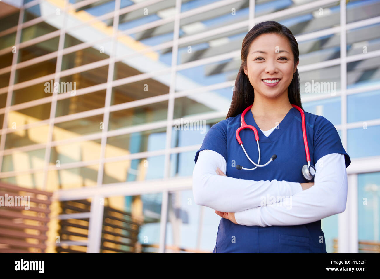Lächelnd asiatische Frau healthcare Arbeiter mit gekreuzten Armen Stockfoto