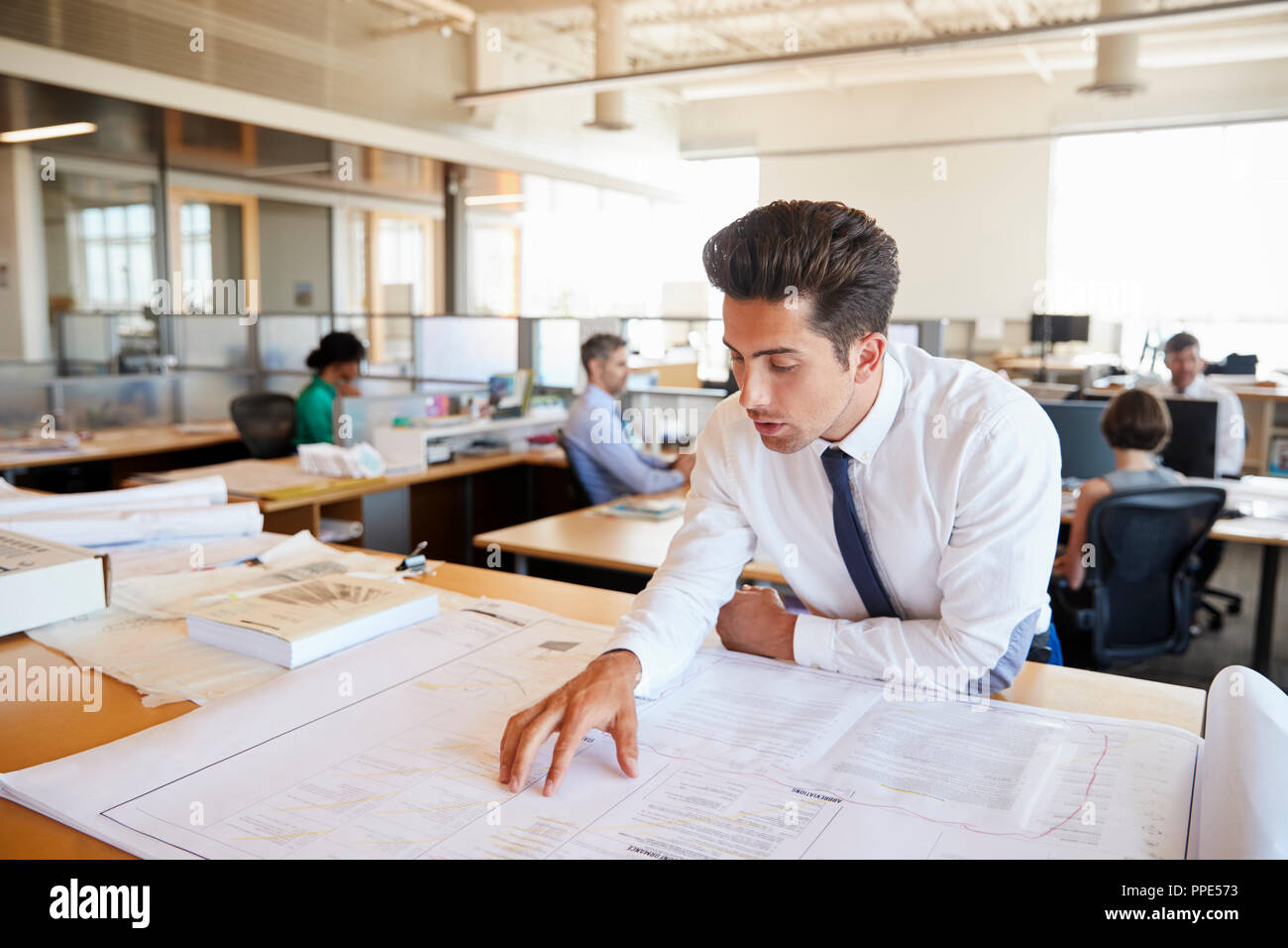 Junge männliche Architekt Studium der Pläne im Großraumbüro Stockfoto