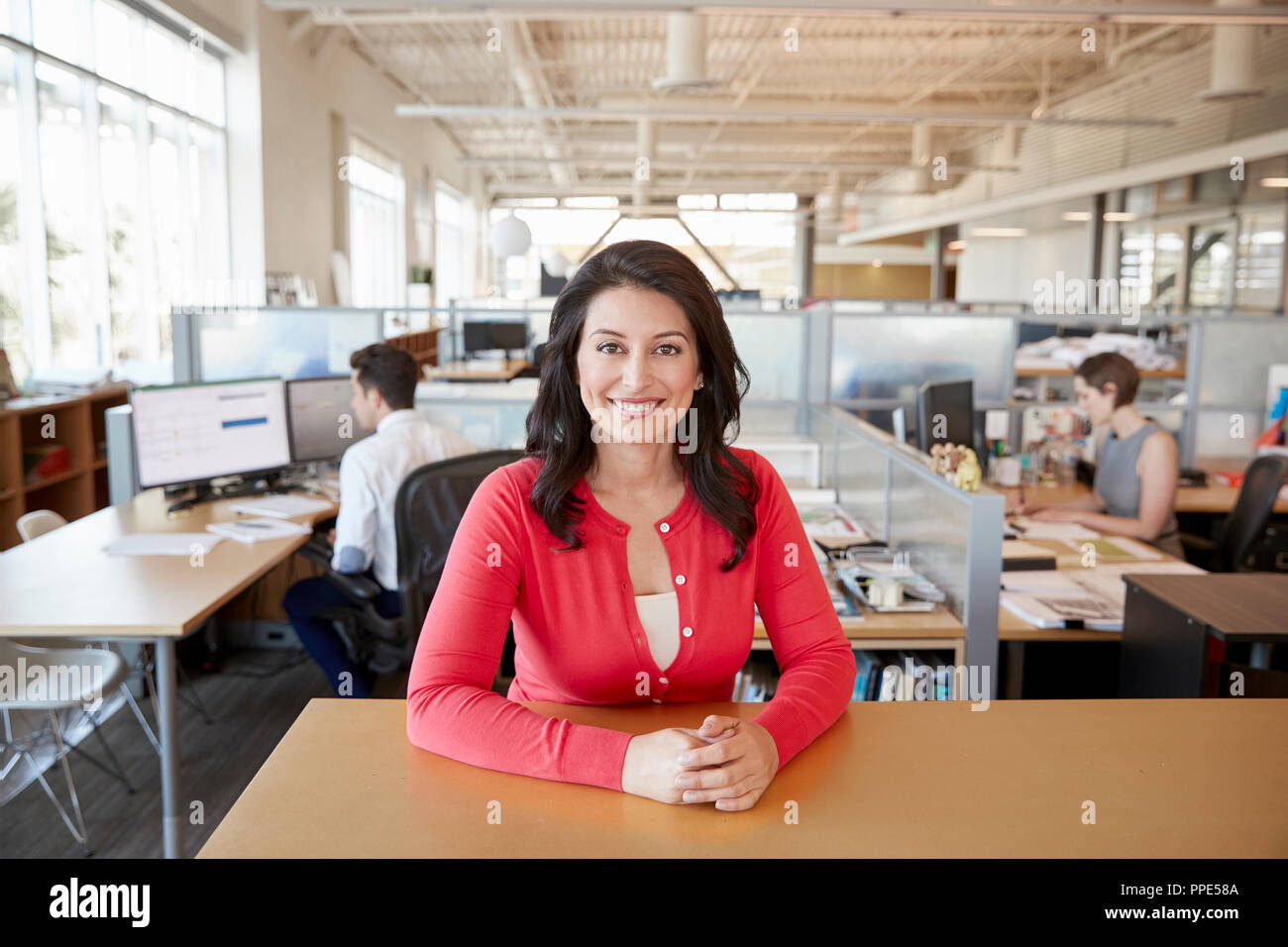 Lächelnd weibliche Architekt an einem Schreibtisch in der geschäftigen Großraumbüro Stockfoto