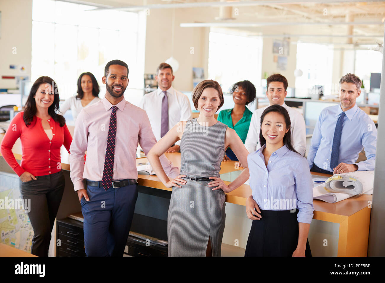 Kollegen lächeln in die Kamera in einem Großraumbüro Stockfoto