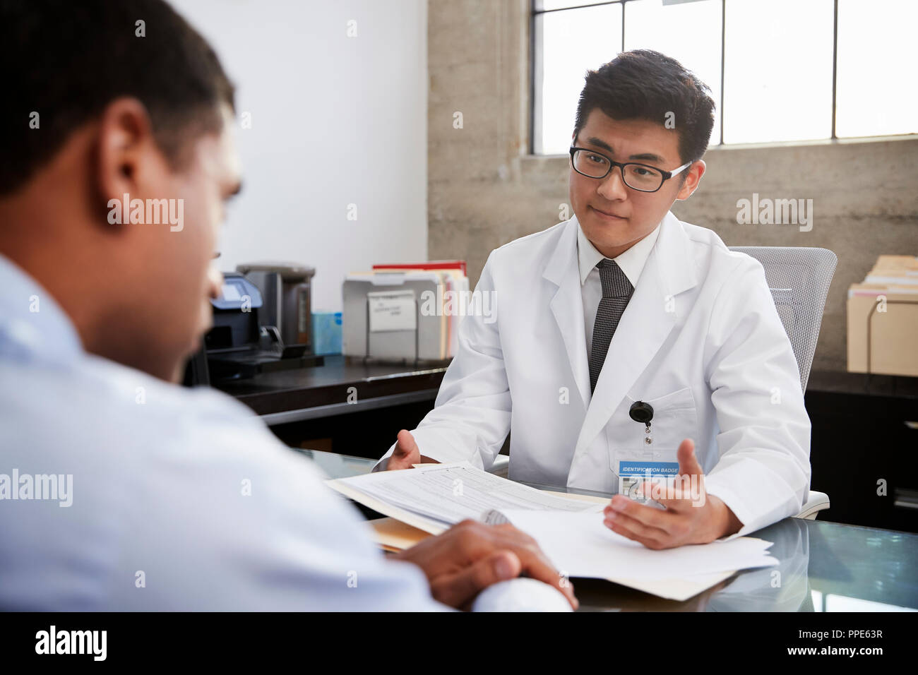 Jungen Asiatischen männlicher Arzt in Absprache mit männlichen Patienten Stockfoto