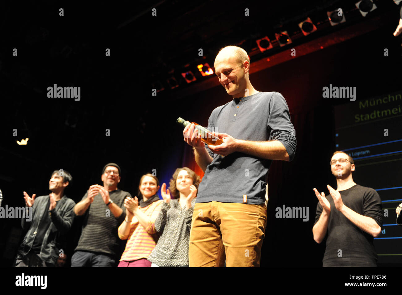 Sieger Alex Burkhard mit einer Flasche Whiskey als der Preis der Münchner Poetry Slam Meisterschaft 2015 in der Volksstheater. Stockfoto