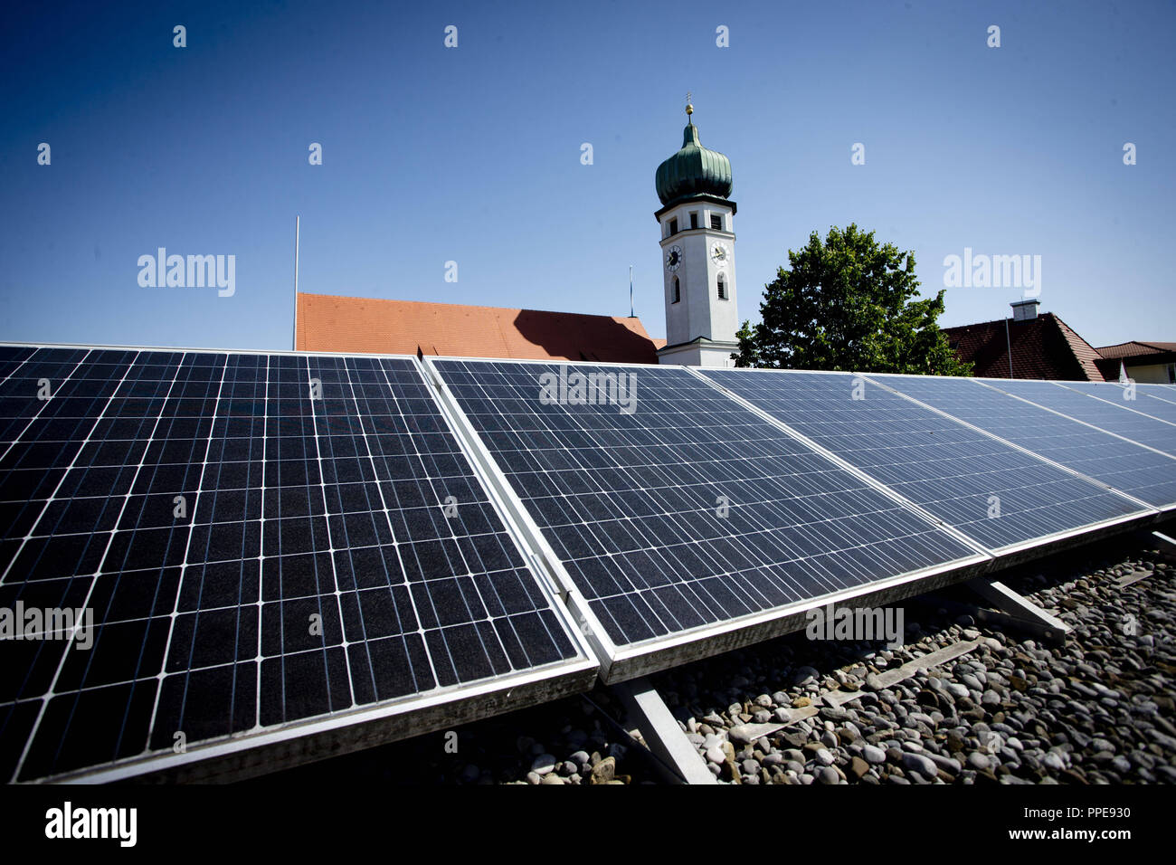 Photovoltaik-anlage auf einem Hausdach vor einem Kirchturm. Stockfoto
