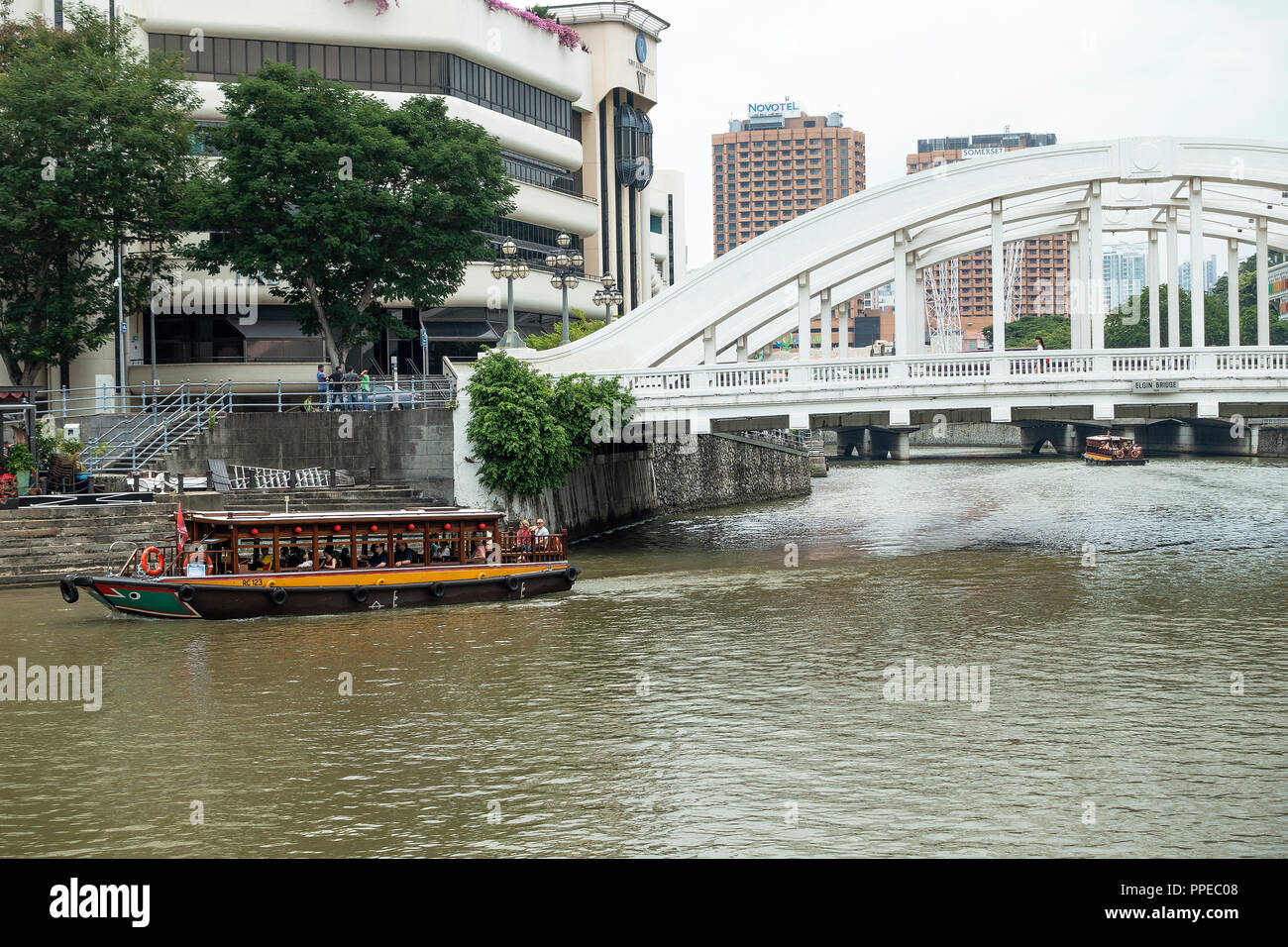 Die Elgin Bridge River Crossing mit touristischen Taxi Boot auf dem Singapore River mit dem Riverwalk Eigentumswohnung Gebäude in Singapur Asien Stockfoto