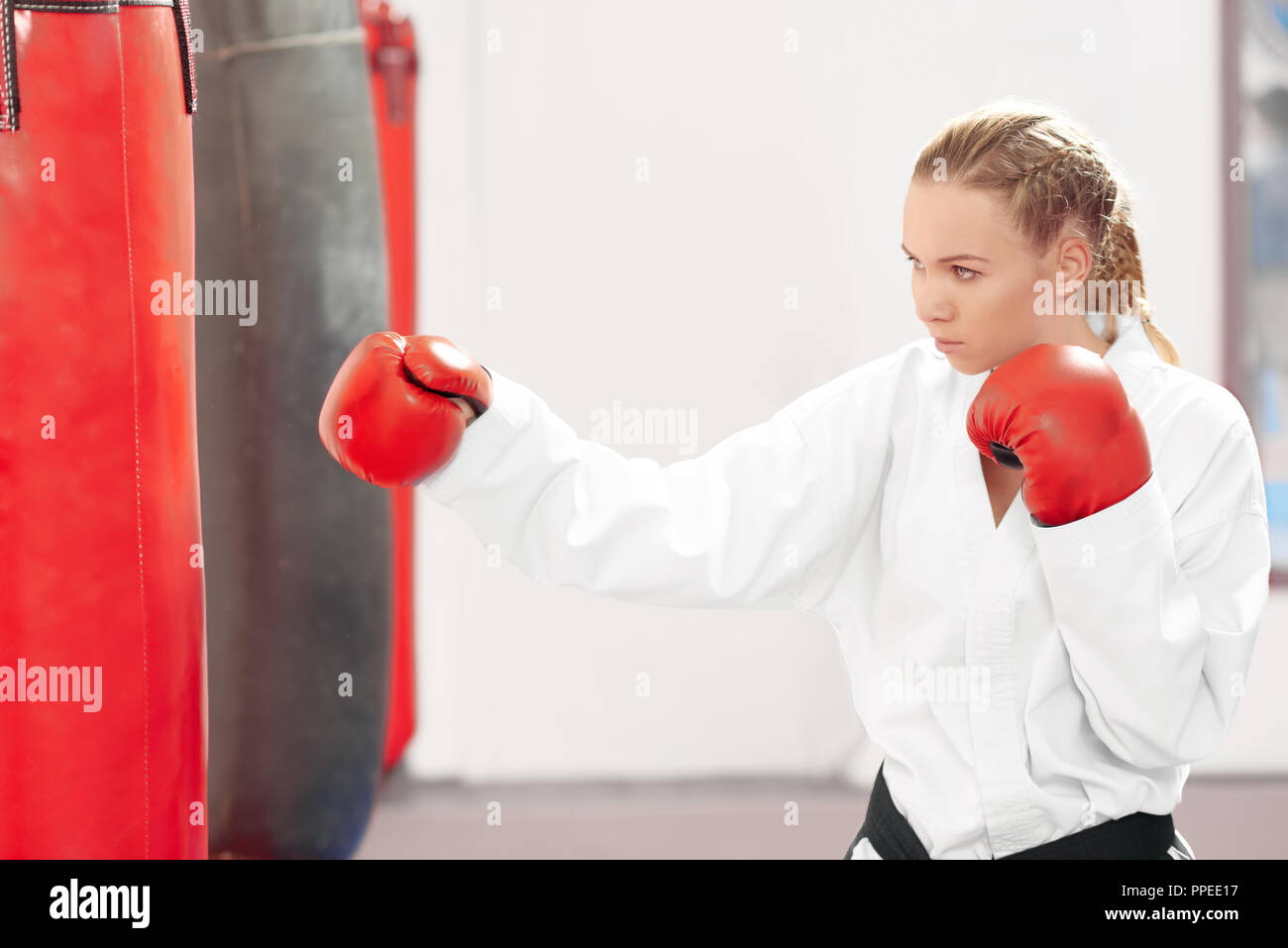Ernst hübsche Frau schlagen Boxing Boxsack in der Turnhalle. Sportliche  Karate Mädchen, tragen im Kimono und roten Schutzhandschuhe Verbesserung  der Technik der Kampf im Hard Mixed Martial Arts Training Stockfotografie -  Alamy
