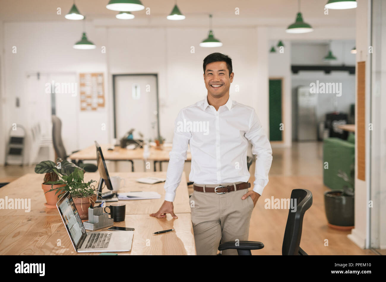 Lächelnd asiatische Geschäftsmann auf seinem Schreibtisch in einem Büro Stockfoto