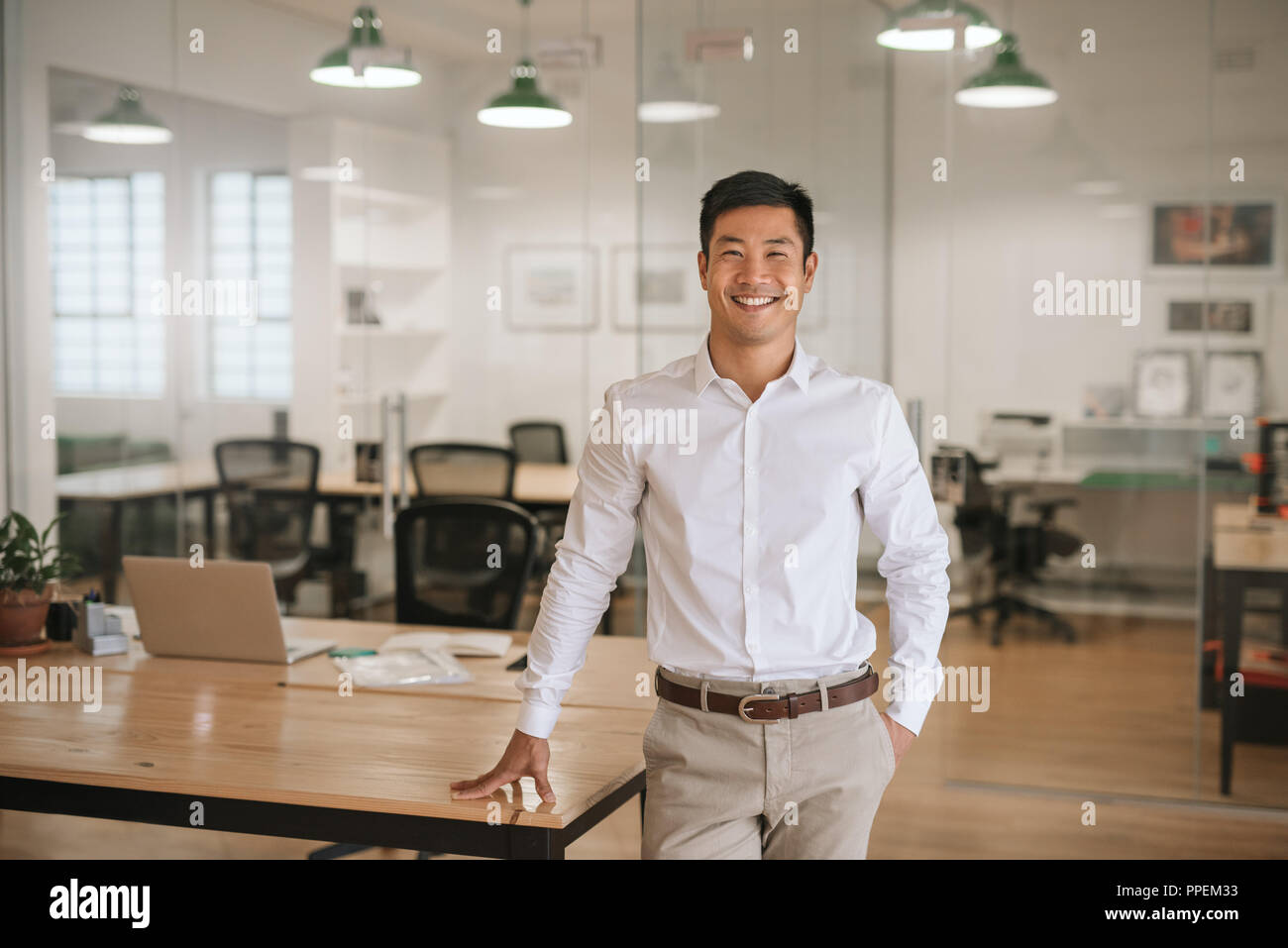 Junge asiatische Geschäftsmann stehend in einem Büro selbstbewusst lächelnd Stockfoto