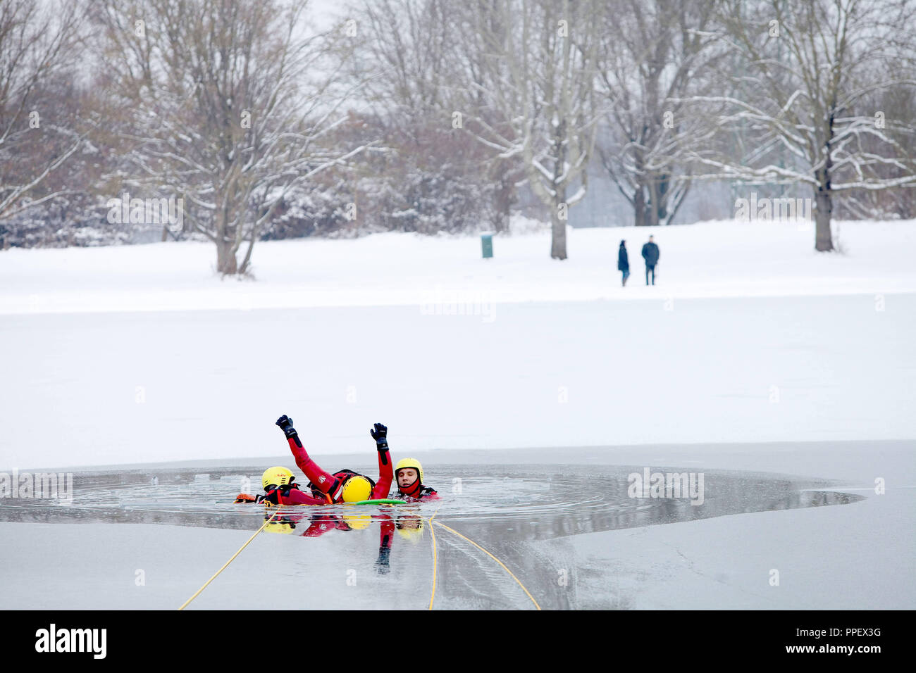 Bei einem Eis rescue Ausbildung der Wasserwacht Unterföhring auf feringa See die Retter auch in das Wasser erhalten, um das Opfer zu bringen, die durch das Eis gefallen ist, auf einem Scoop Stretcher (Wirbelsäule), damit er sich aus dem Wasser gezogen werden. Stockfoto