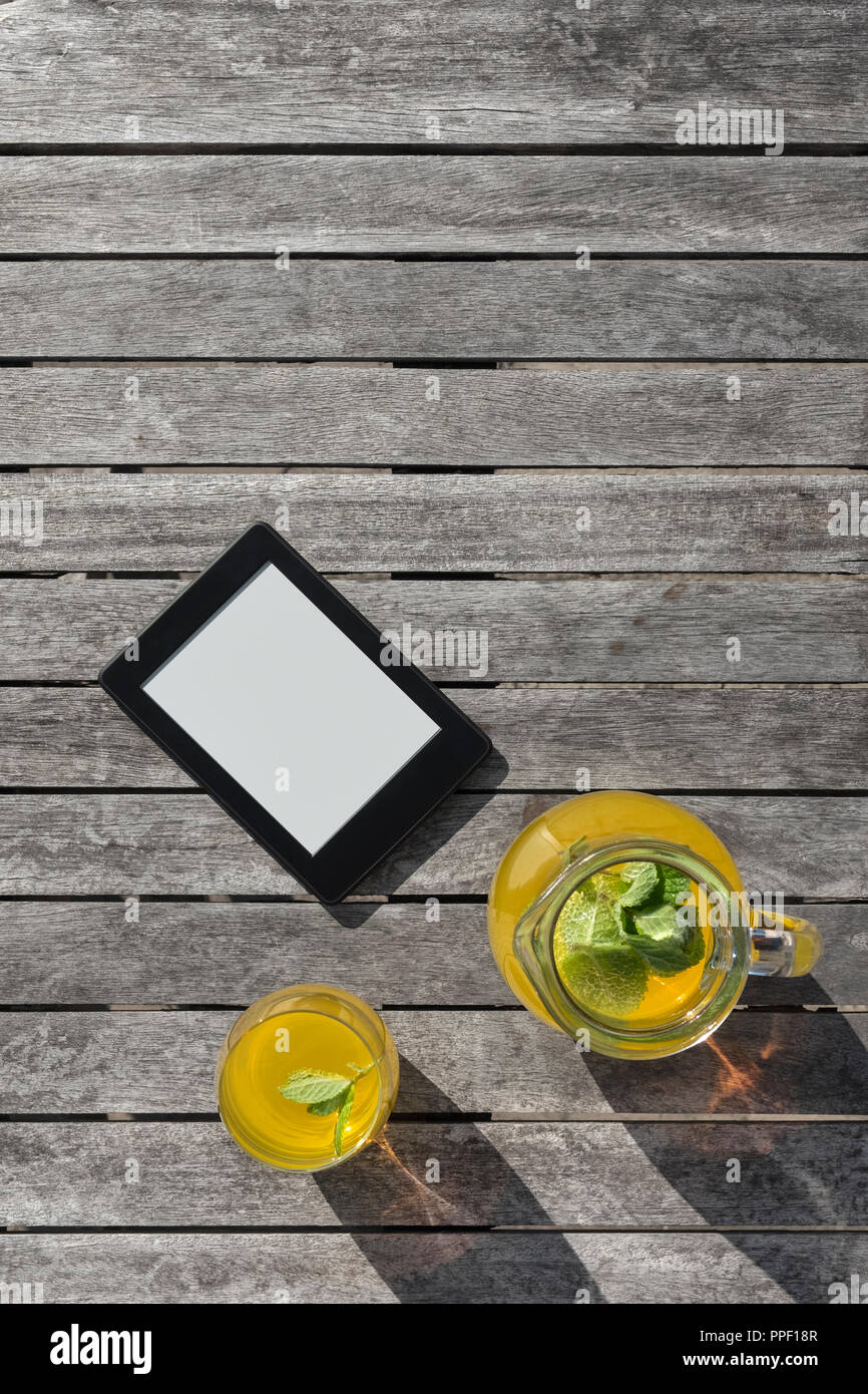 E-Reader und ein Glas Obst Drink auf einem Holztisch. Stockfoto