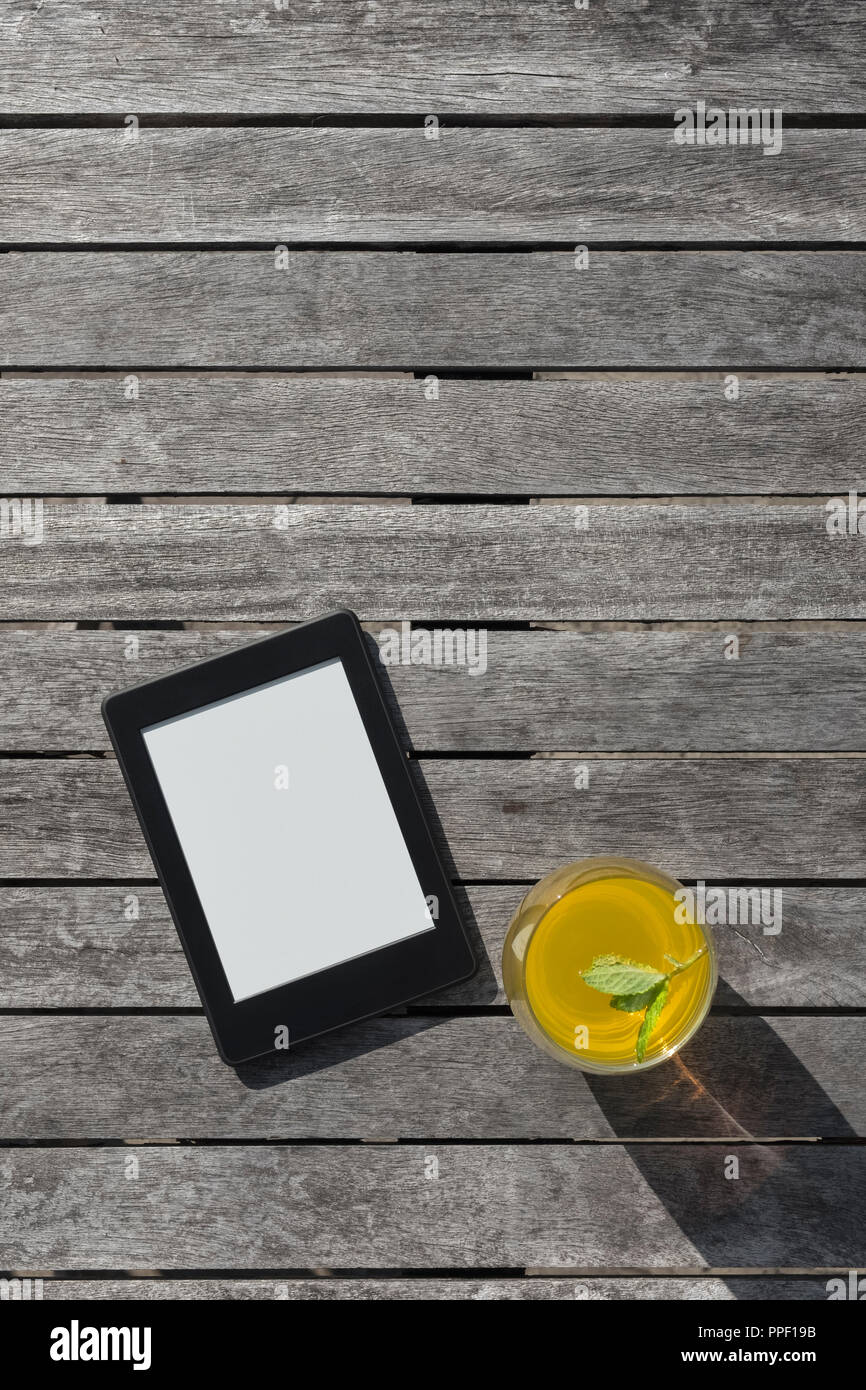 E-Reader und ein Glas Obst Drink auf einem Holztisch. Stockfoto