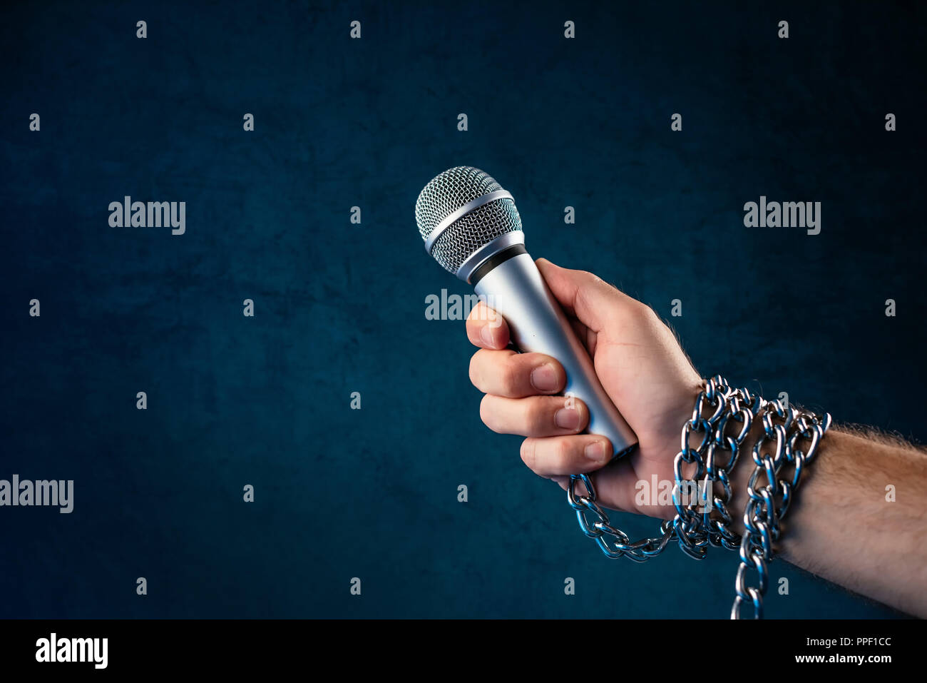 Die Freiheit der Presse und Journalismus, konzeptionelle Bild mit Mikrofon in männlicher Hand mit Ketten, Low Key Image gebunden Stockfoto