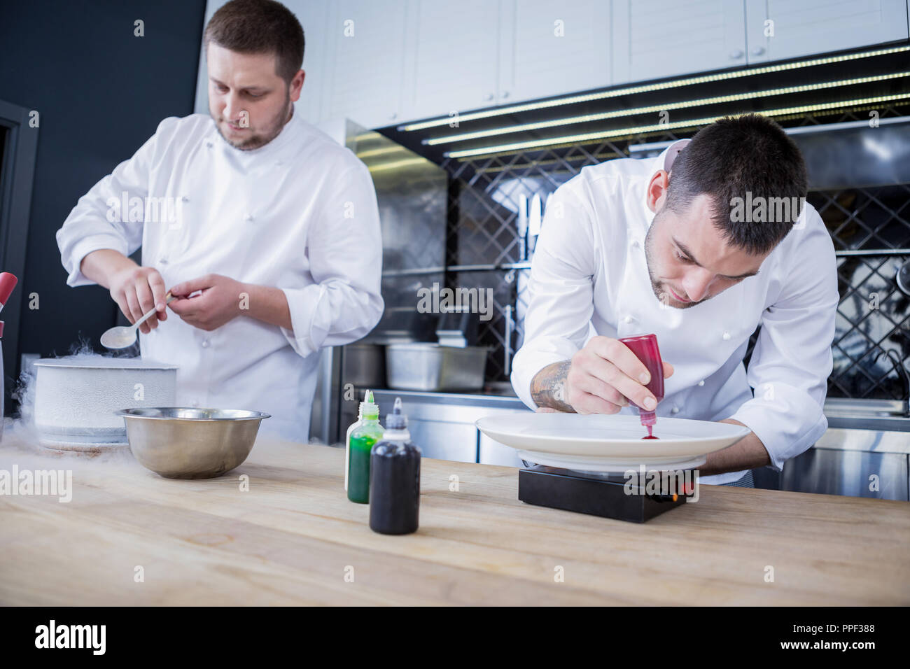 Geschäftige Köche kochen verschiedene Gerichte in der Küche Stockfoto