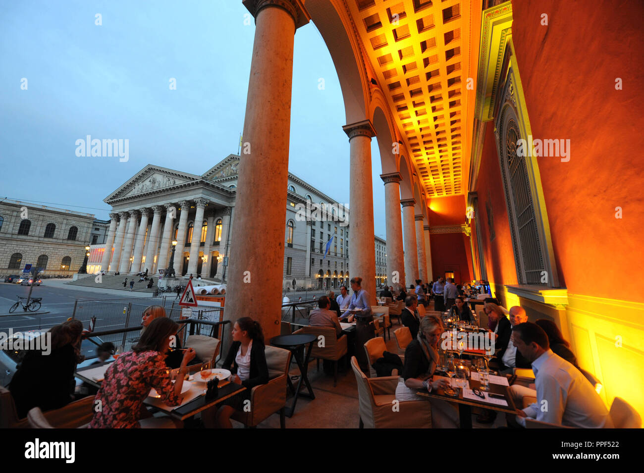 Gäste können auf der Terrasse des Restaurants "kufflers California Kitchen" in das Gebäude der ehemaligen Residenzpost auf den Max-Joseph-Platz in München. Im Hintergrund, der Bayerischen Staatsoper. Stockfoto