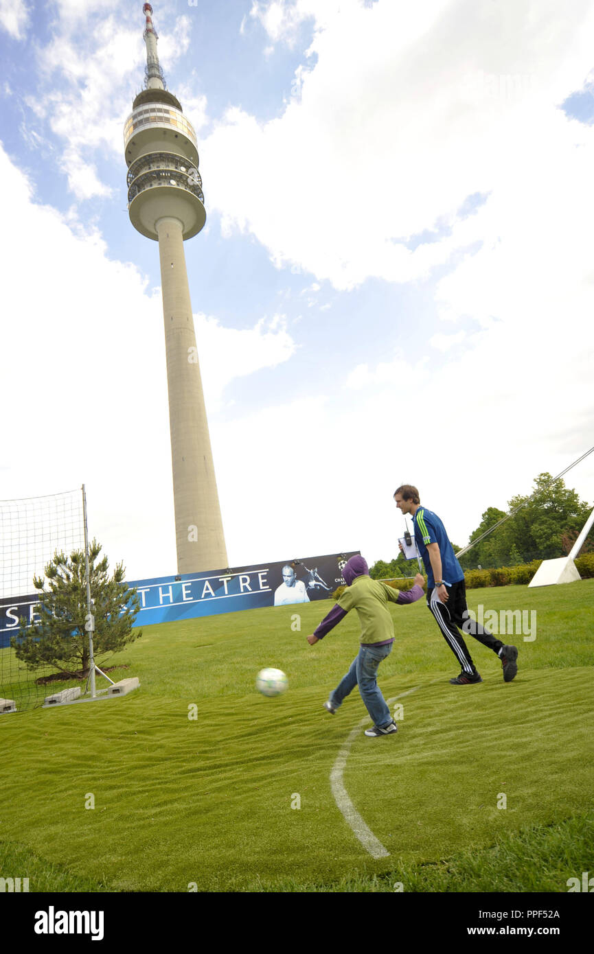 Die Champions Festival im Olympiapark vor dem Champions League Finale FC Bayern gegen FC Chelsea. Vier Tage Fußball-Festival für alle Menschen in München! Das Bild zeigt einen Mann und ein Junge beim kicken den Ball. Im Hintergrund der Olympiaturm. Stockfoto