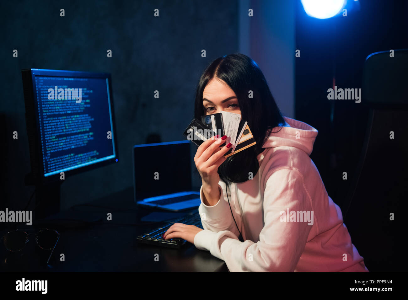 Junger Teenager hacker Mädchen in Hoodie holding Kreditkarte gegen private Kennwort holding Kreditkarte in der Cyberkriminalität und Internetkriminalität Konzept und Internet Information Security Konzept Stockfoto