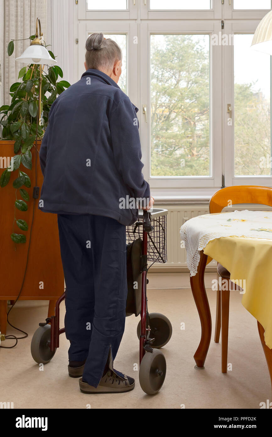 Alte Frau in Ihr Wohnzimmer mit 3-rollator. Ein mobiles Gerät für Leute, die mit balance und Stärke in kleinen Räumen. Stockfoto
