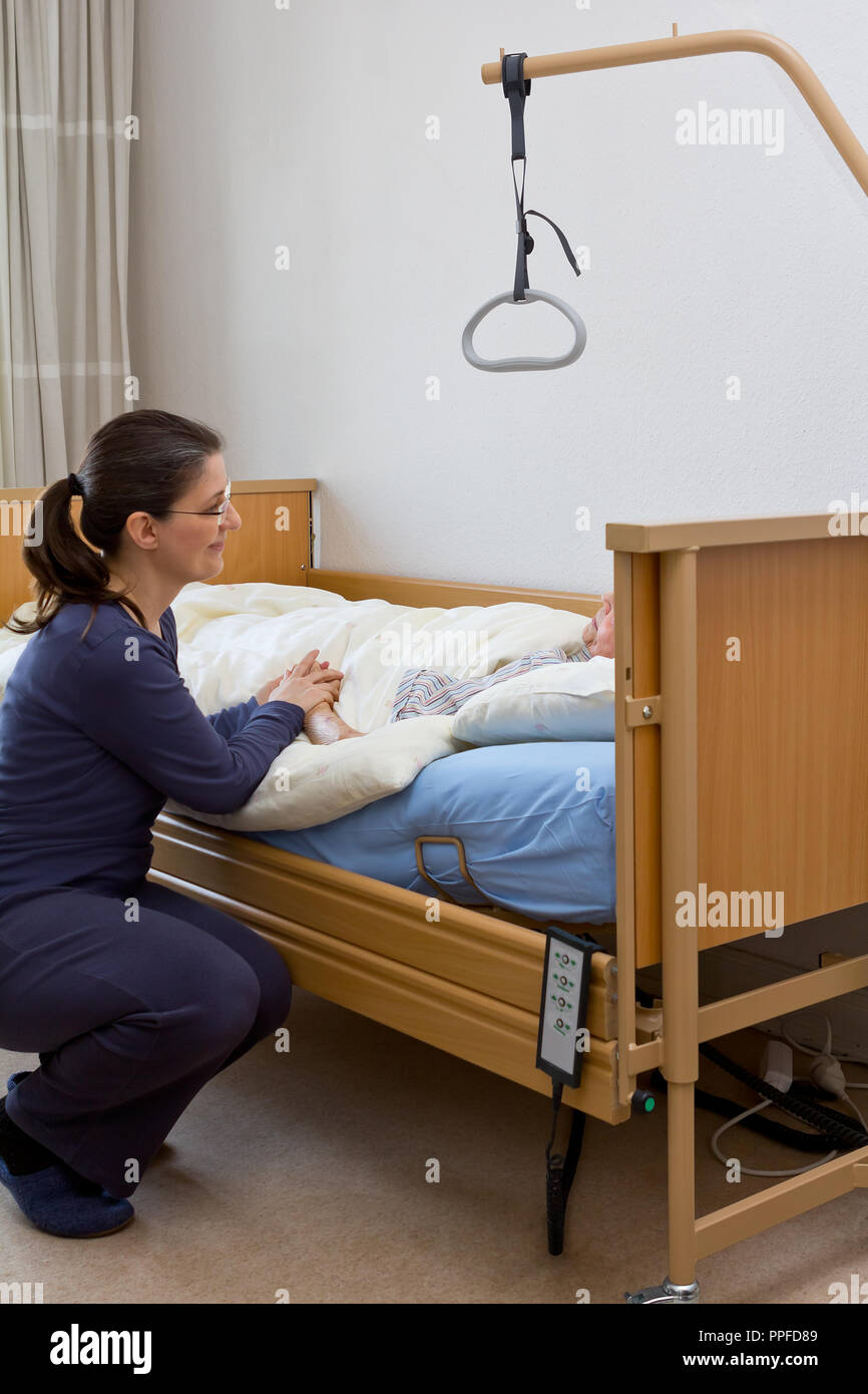 Frau an der Krankenpflege Bett Ihrer unheilbar kranken Großmutter, hielt ihre Hand und sprach zu ihr. Konzept des Sterbens zu Hause oder in einem Hospiz. Stockfoto