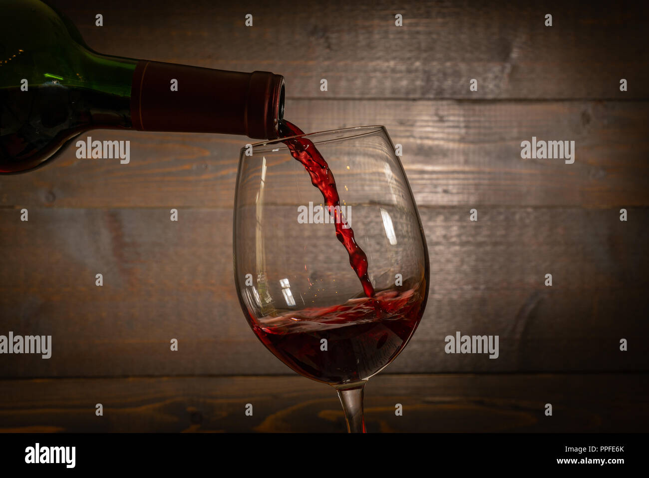 Rotwein Gießen in einem Weinglas aus einer Flasche Stockfoto