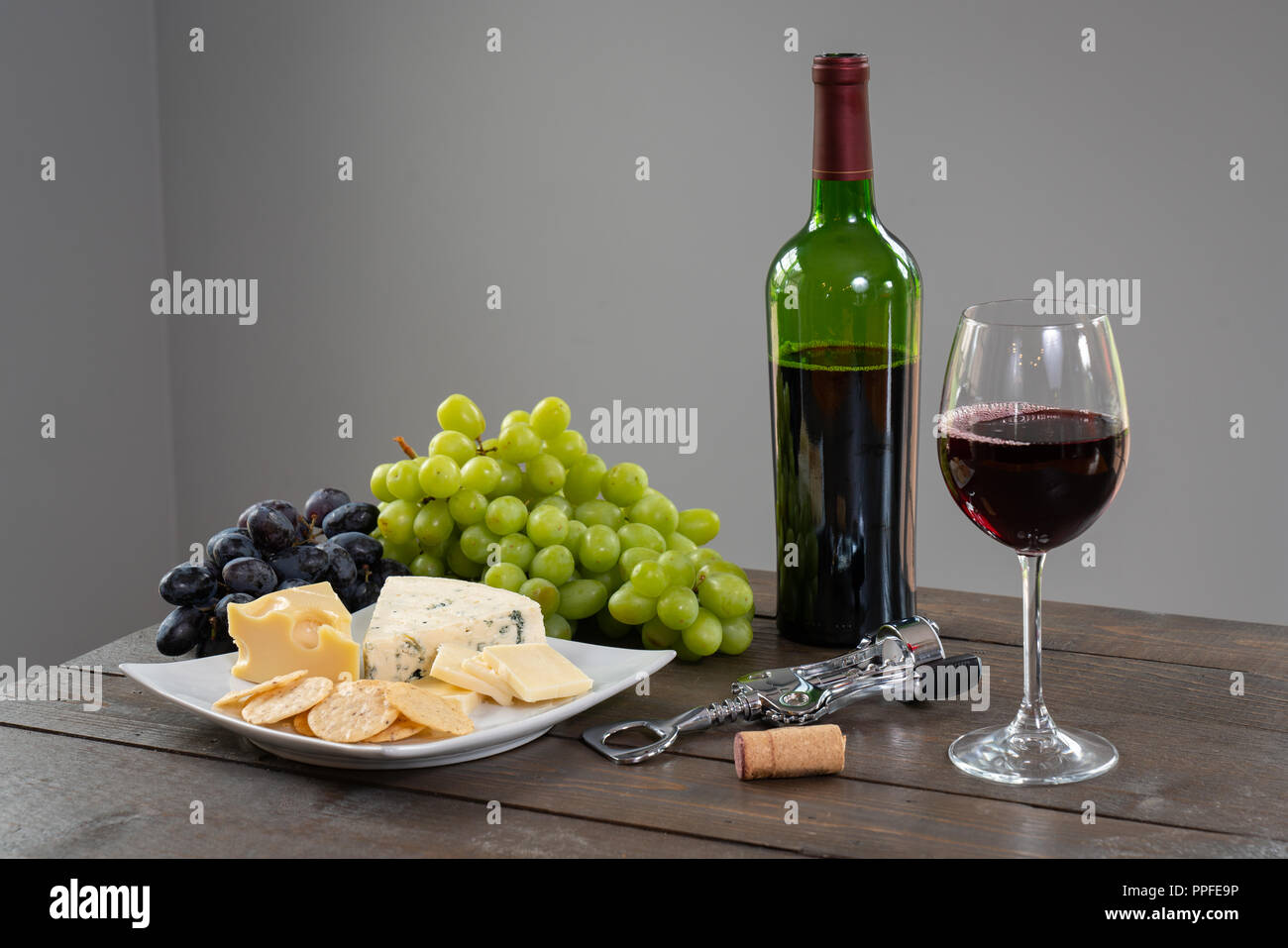 Glas Weißwein mit Flasche Wein, Käse und Trauben Stockfoto