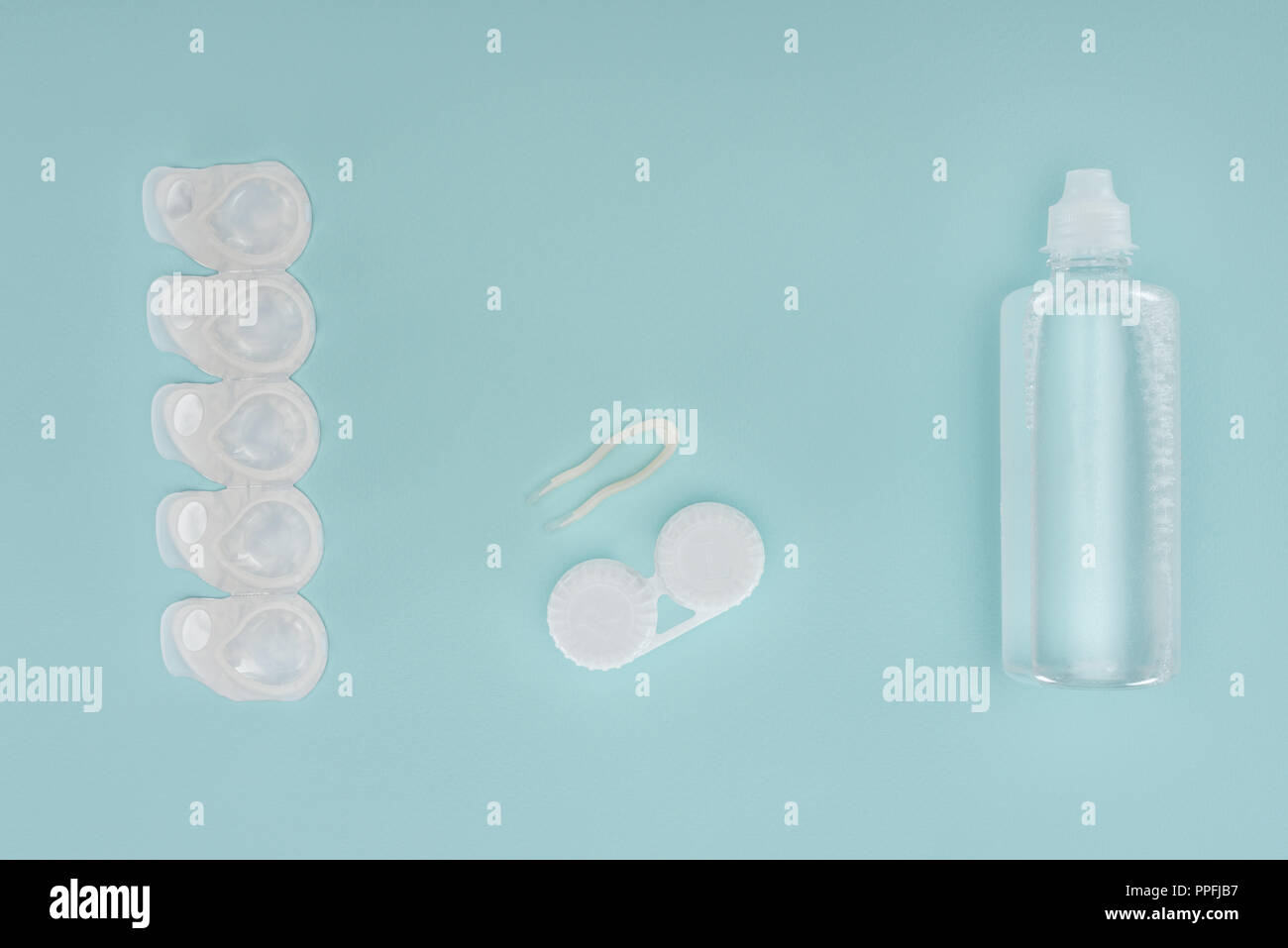 Flach mit steriler Flüssigkeit in der Flasche, Pinzette und Behälter für Kontaktlinsen auf Blau Tischplatte Stockfoto
