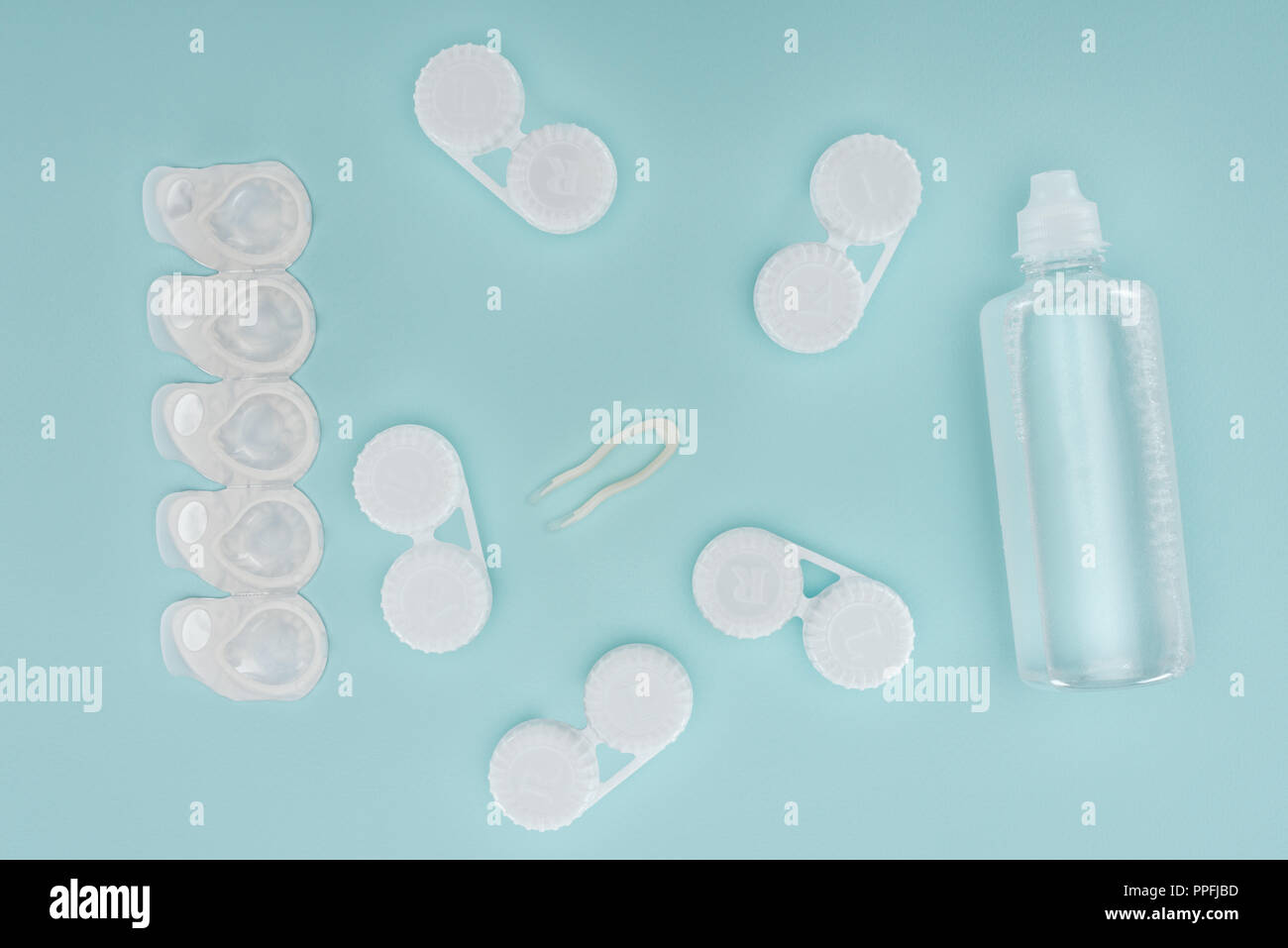 Flach mit steriler Flüssigkeit in der Flasche, Pinzette und Behälter für Kontaktlinsen Storage auf Blau Tischplatte Stockfoto