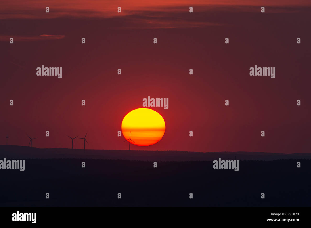 Glühende Sonne und Silhouetten von Windkraftanlagen am Horizont, Sonnenuntergang, Bayern, Deutschland Stockfoto