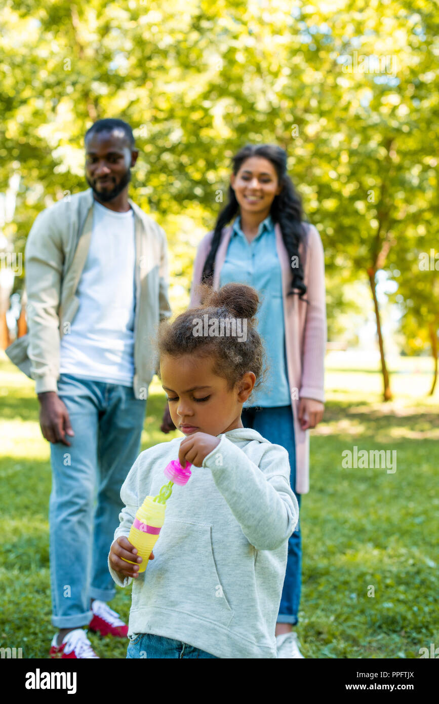 Afrikanische amerikanische Tochter holding Flasche für die Herstellung von Seifenblasen in Park Stockfoto