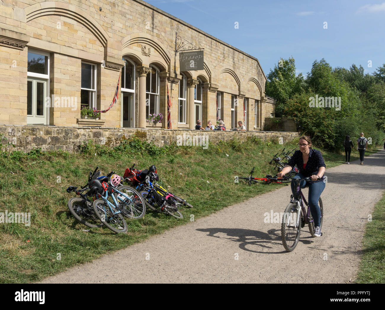 Weibliche Radfahrer auf der Monsal Trail vorbei an den alten Hassop Bahnhof, jetzt ein Café und Buchhandlung; Derbyshire, Großbritannien Stockfoto