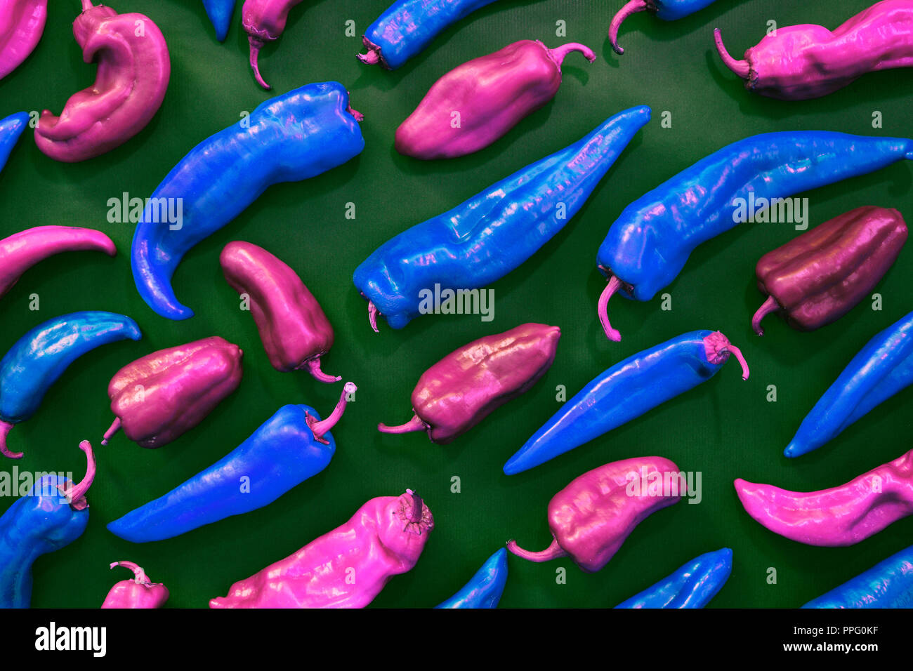 Blau und Rosa Pfeffer Formen kreativen Muster auf grünem Hintergrund. Gemüse und Essen zahlen Abstrakt bunten Hintergrund. Ansicht von oben. Pop Art Stil Stockfoto